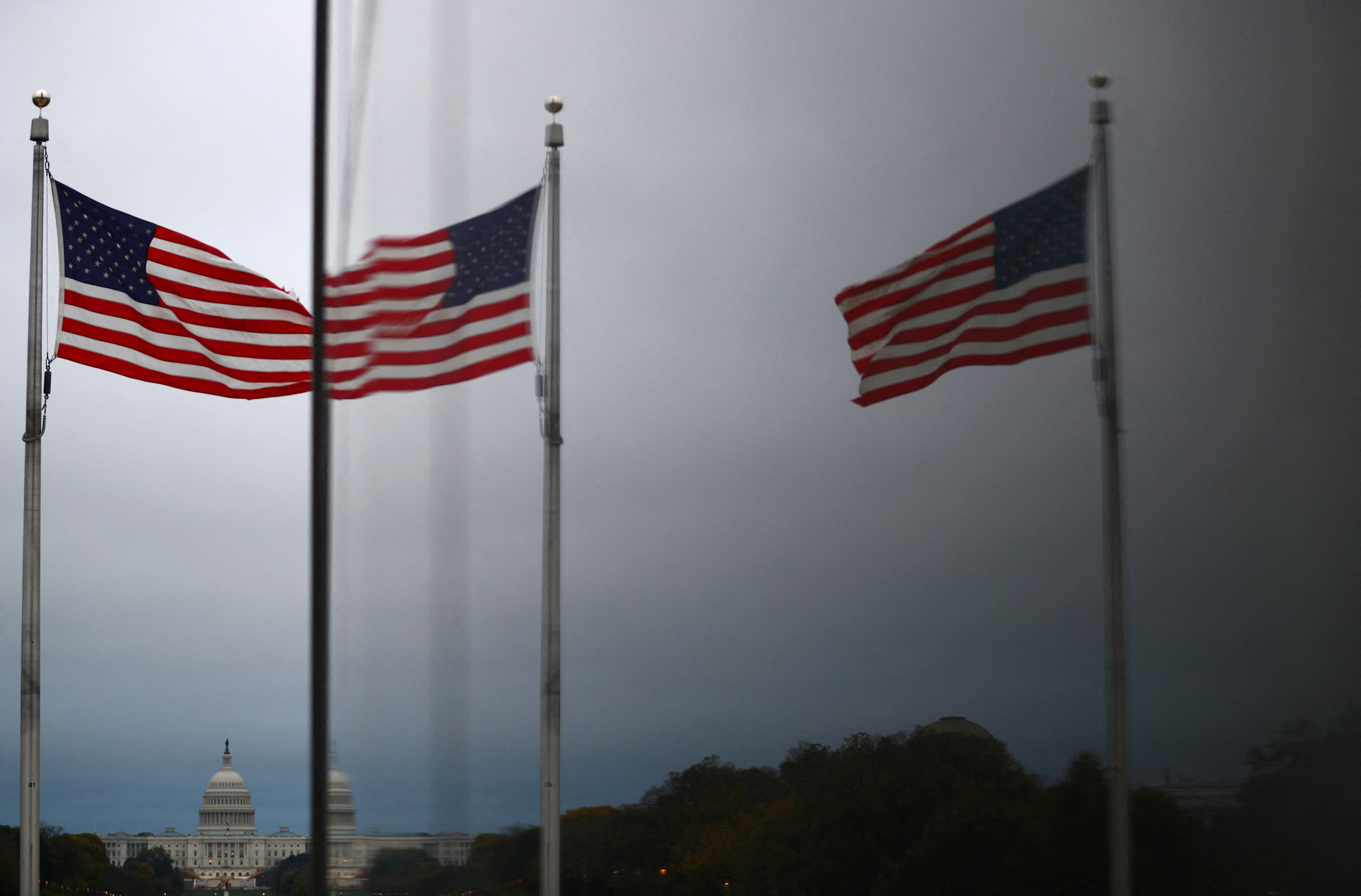 The United States Capitol and U.S flags are reflected in a window in Washington
