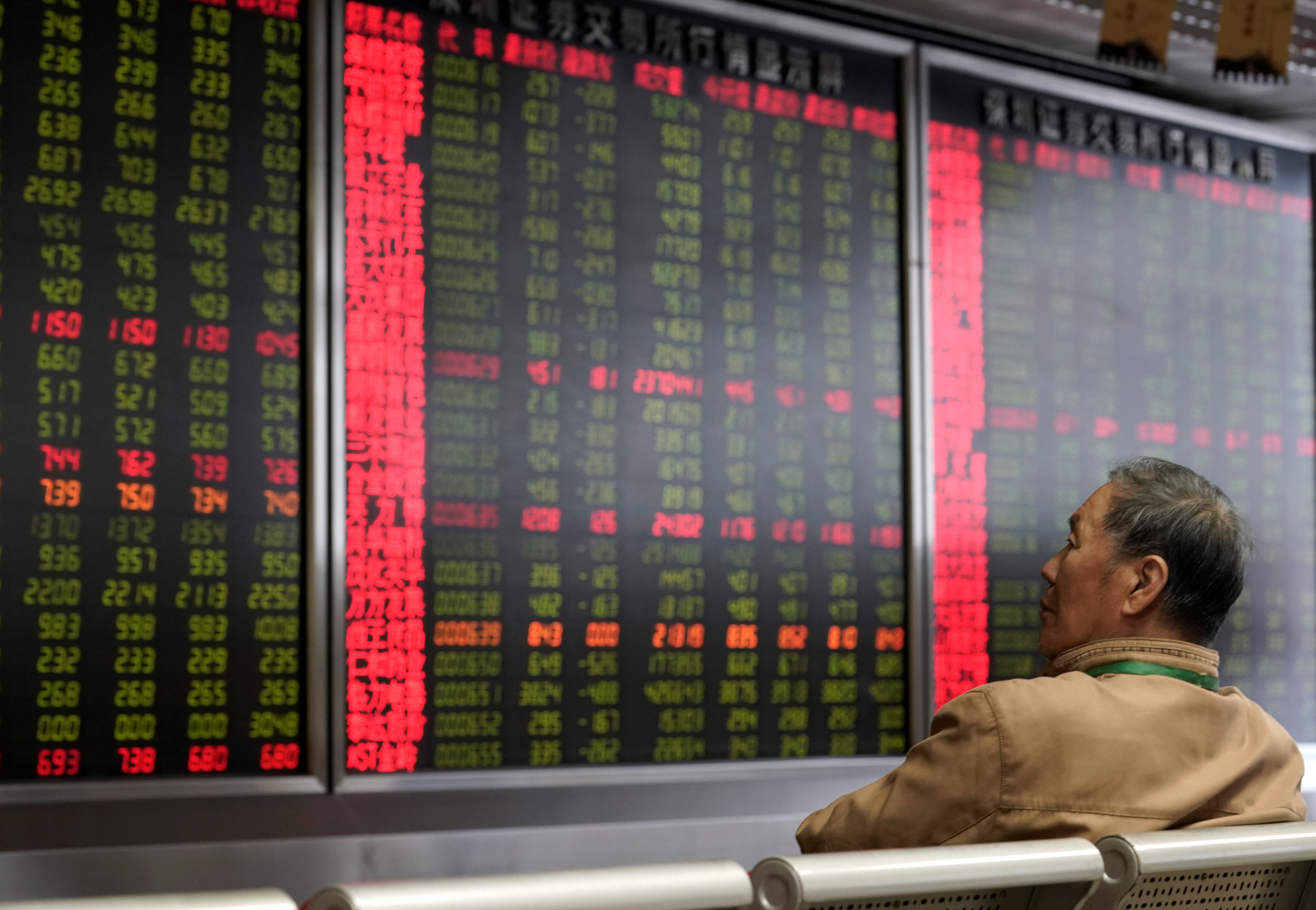 An investor watches a board showing stock information at a brokerage office in Beijing