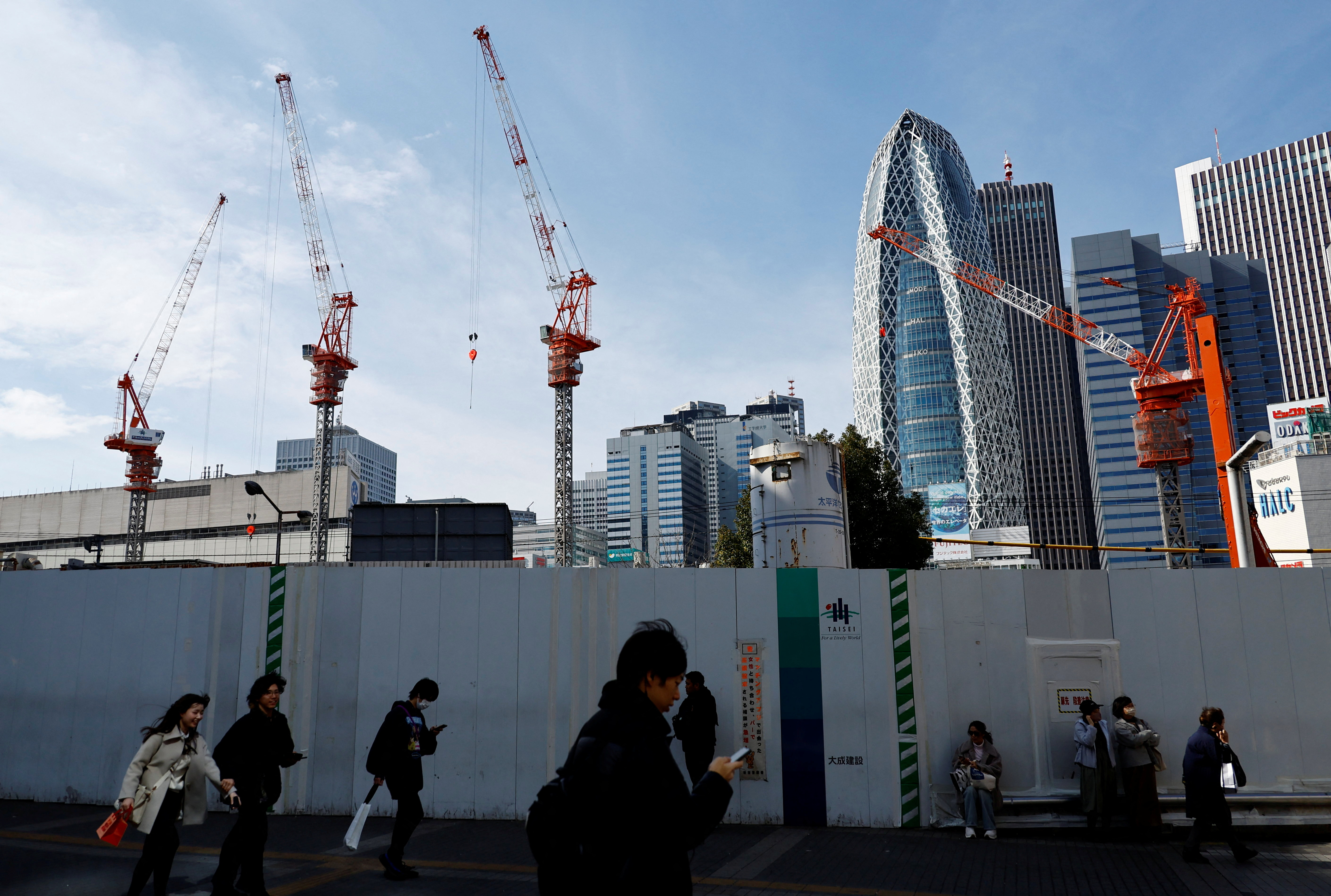 Passersby walk in front of a construction site in Tokyo