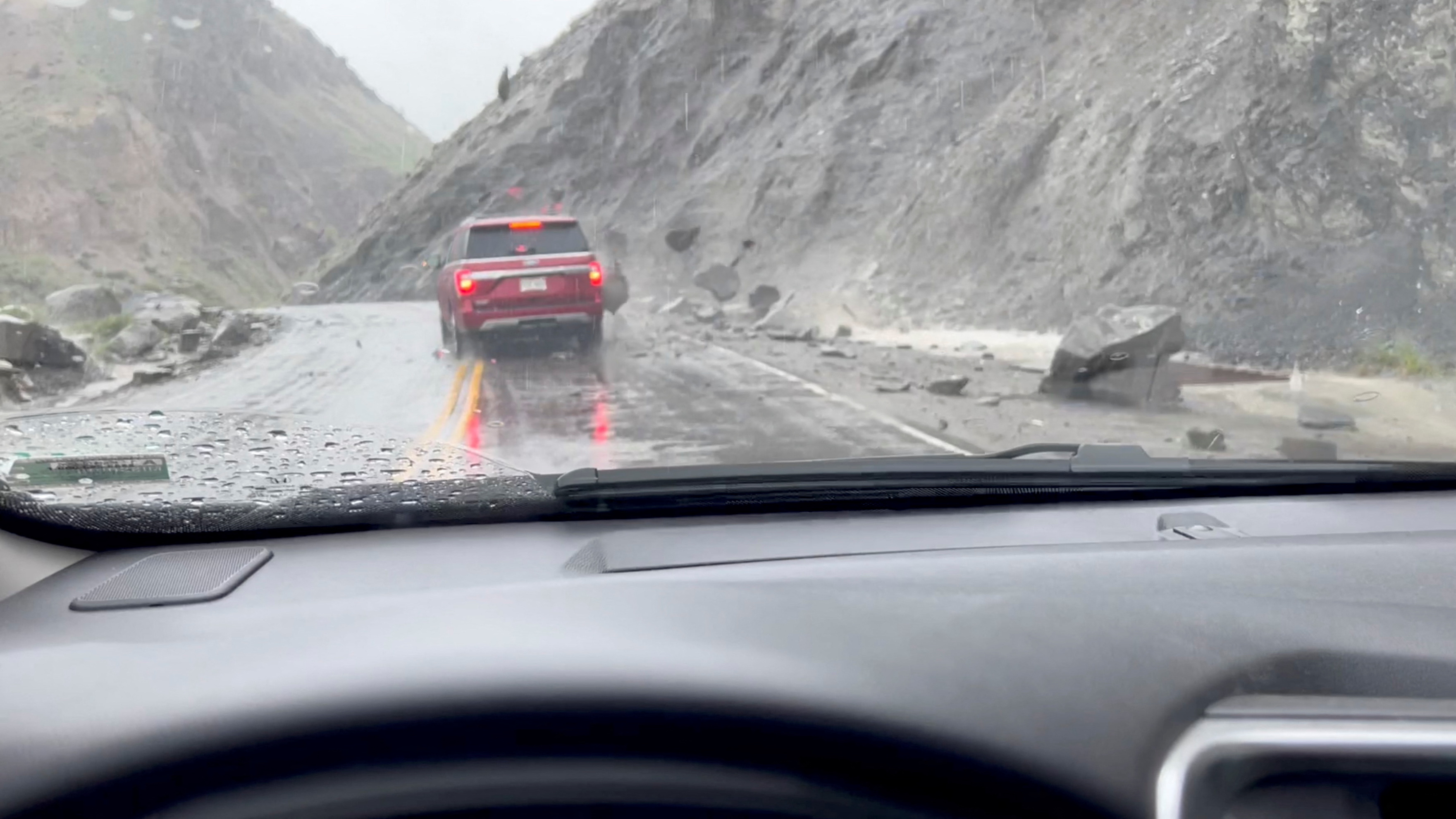 A view shows rocks sliding down the side of a hill and hitting a car at the North Entrance of Yellowstone National Park in Gardiner