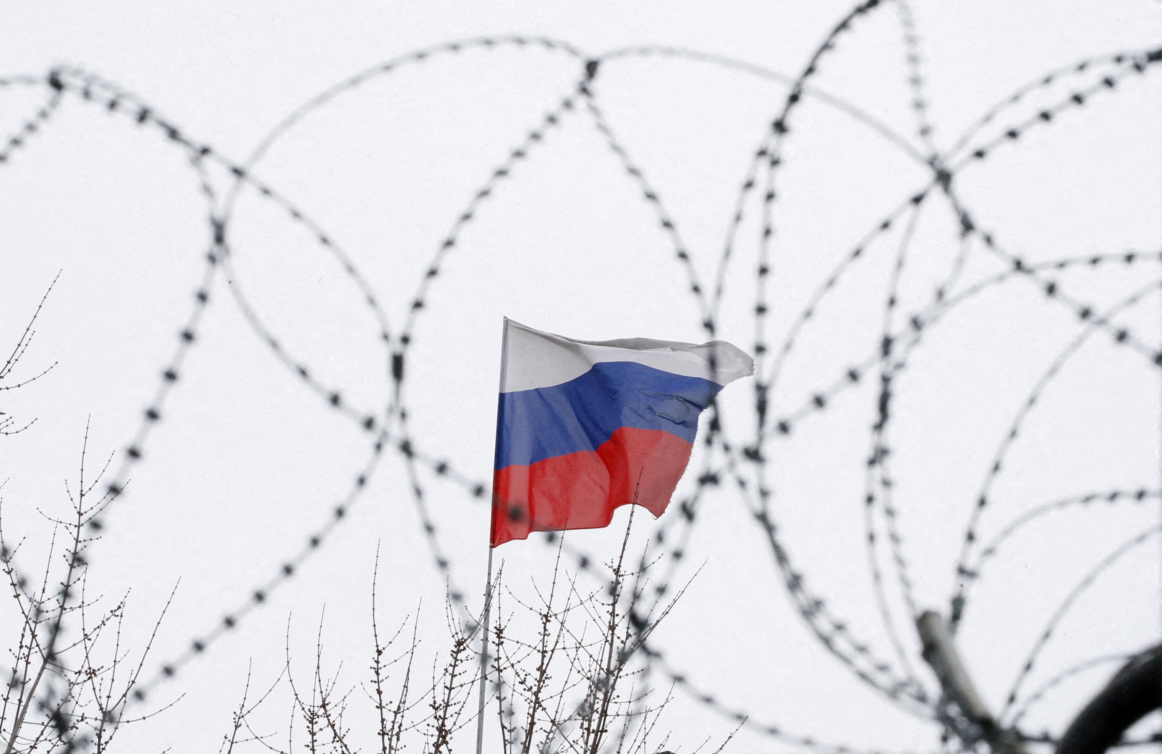 The Russian flag is seen through barbed wire as it flies on the roof of the Russian embassy in Kiev