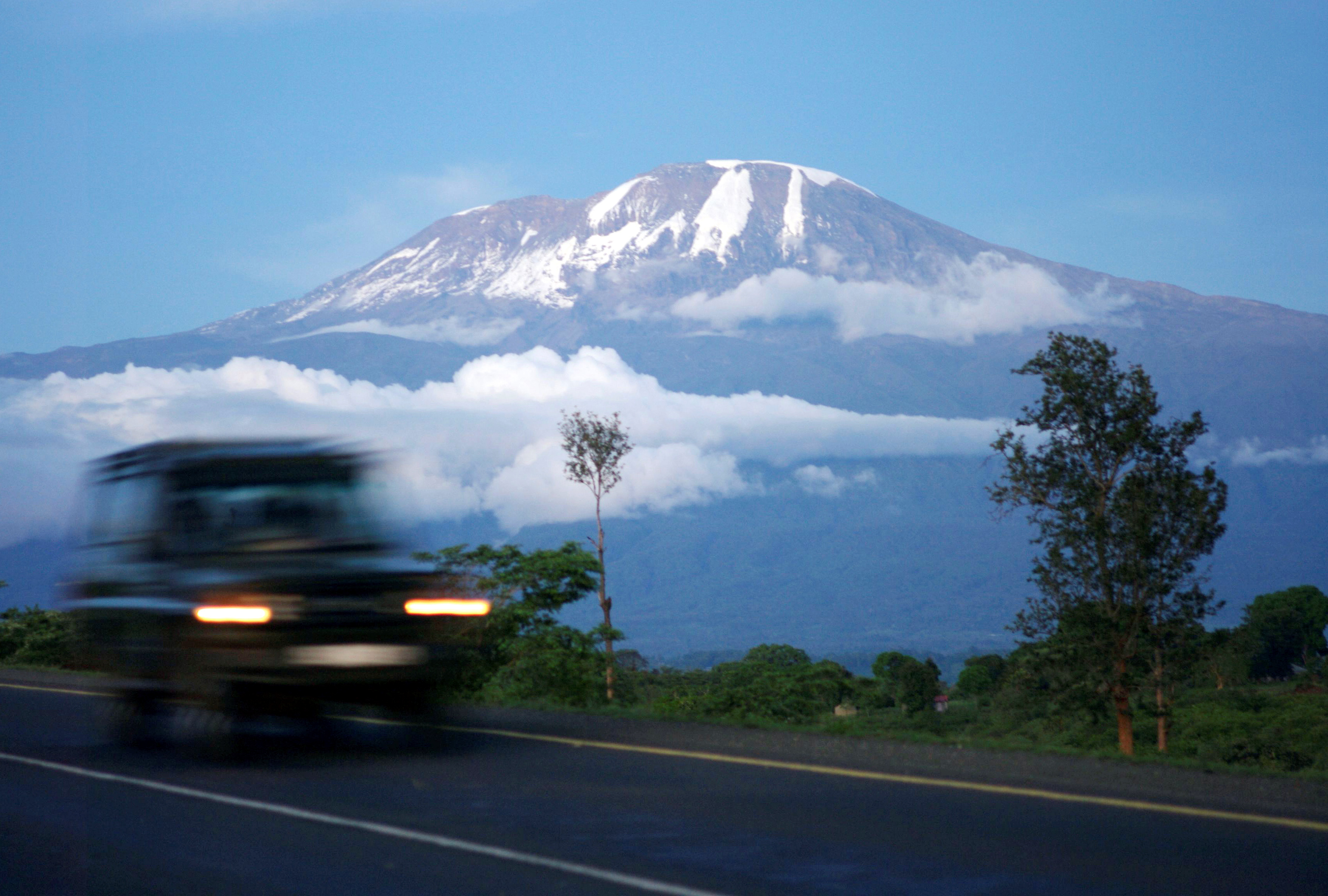 A vehicle drives past Mount Kilimanjaro in Tanzania's Hie district