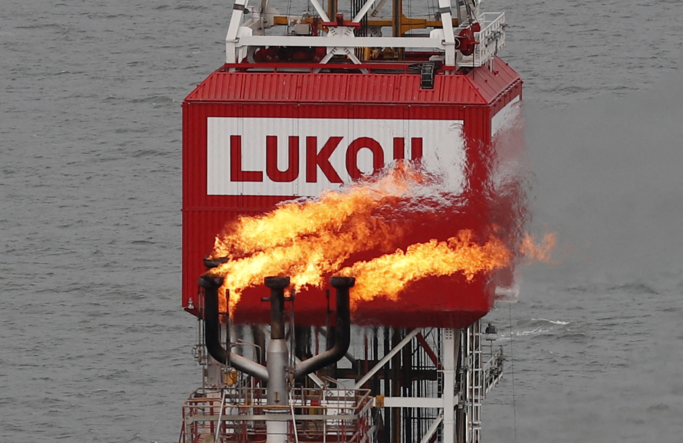 A gas torch is seen next to the Lukoil company sign at the Filanovskogo oil platform in the Caspian Sea