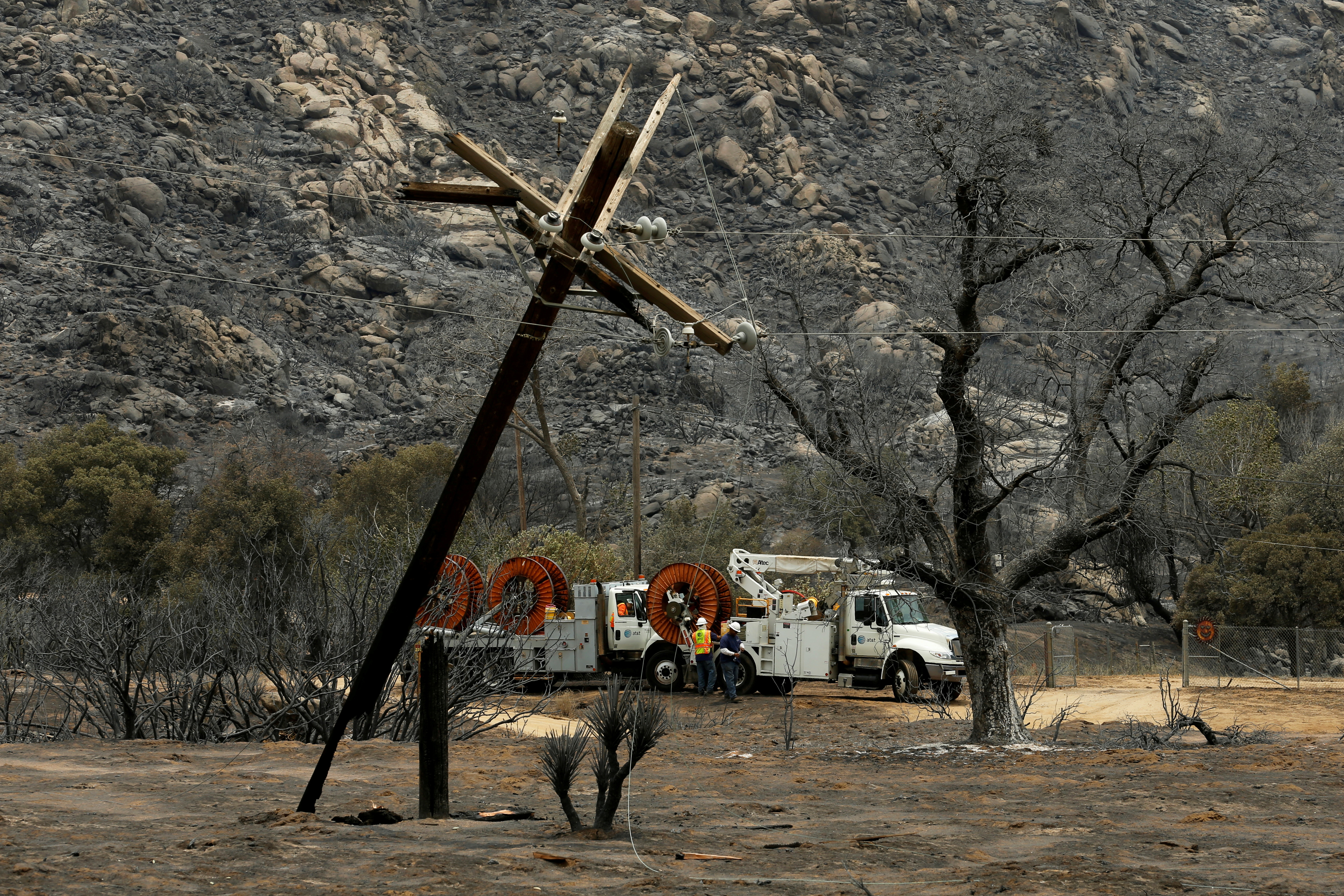 Utility workers begin work repairing power and data lines after a wildfire near Potrero, California, U.S. June 21, 2016. REUTERS/Mike Blake