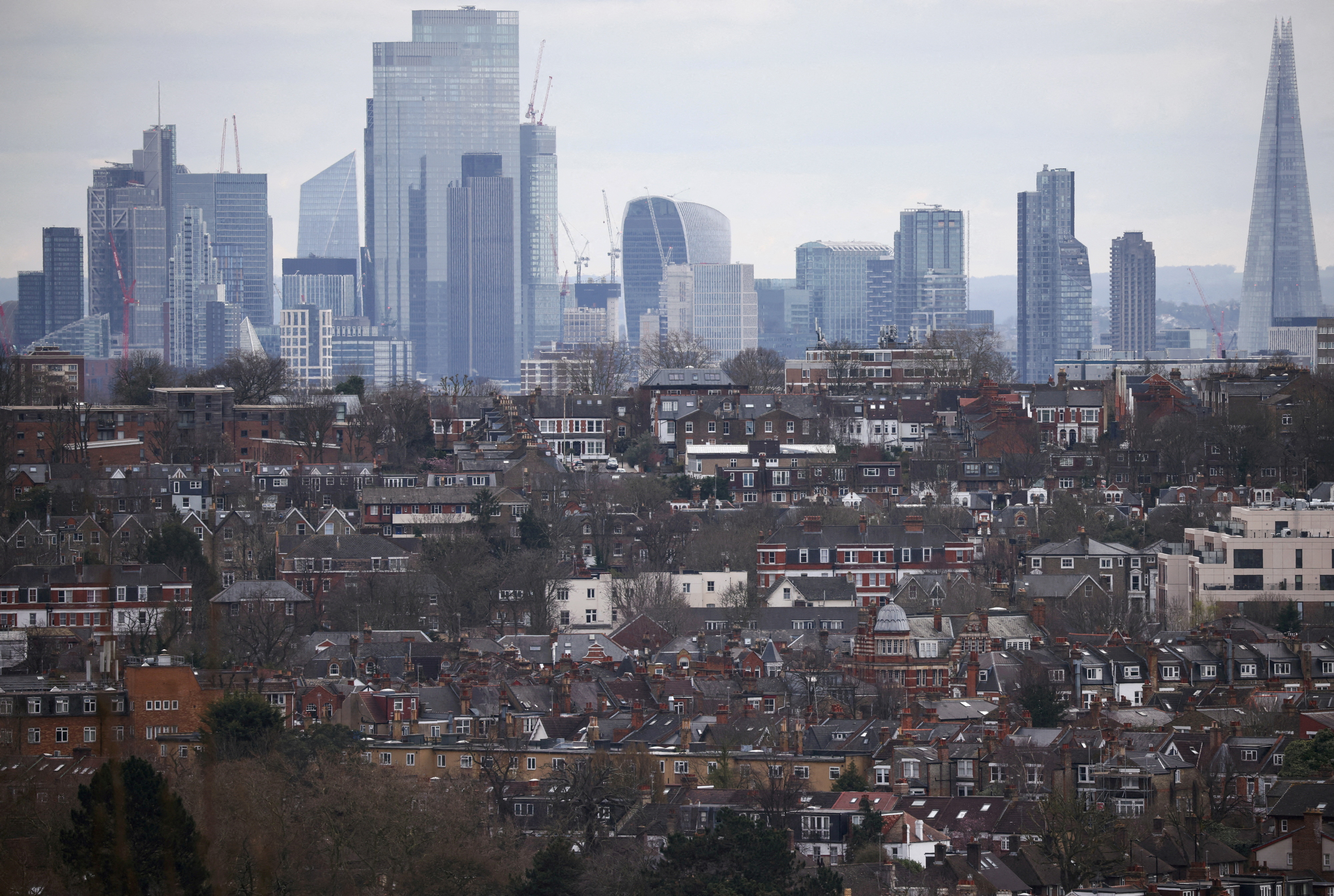 Rows of houses lie in front of the City of London skyline in London