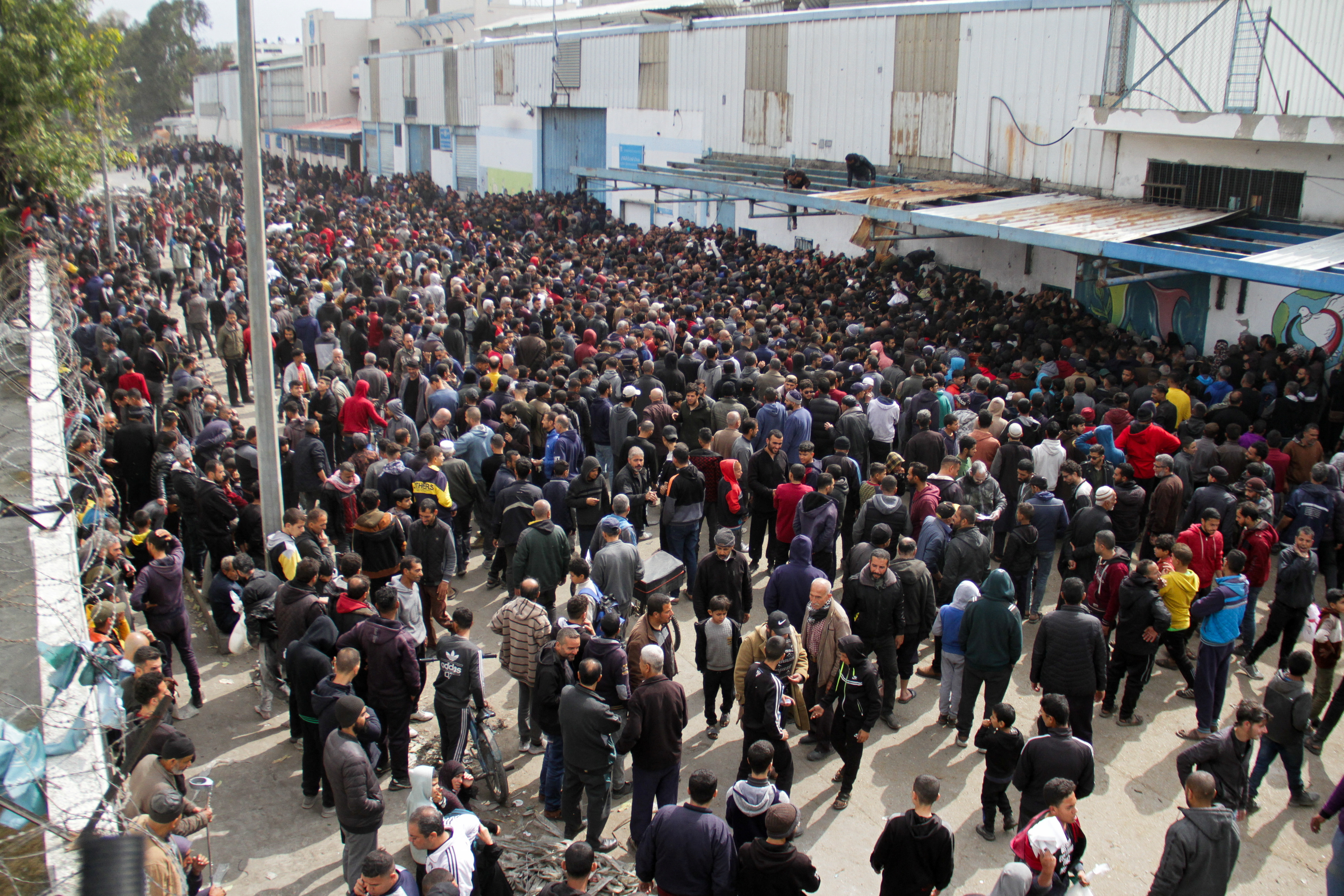 Palestinians gather to receive aid outside an UNRWA warehouse in Gaza City