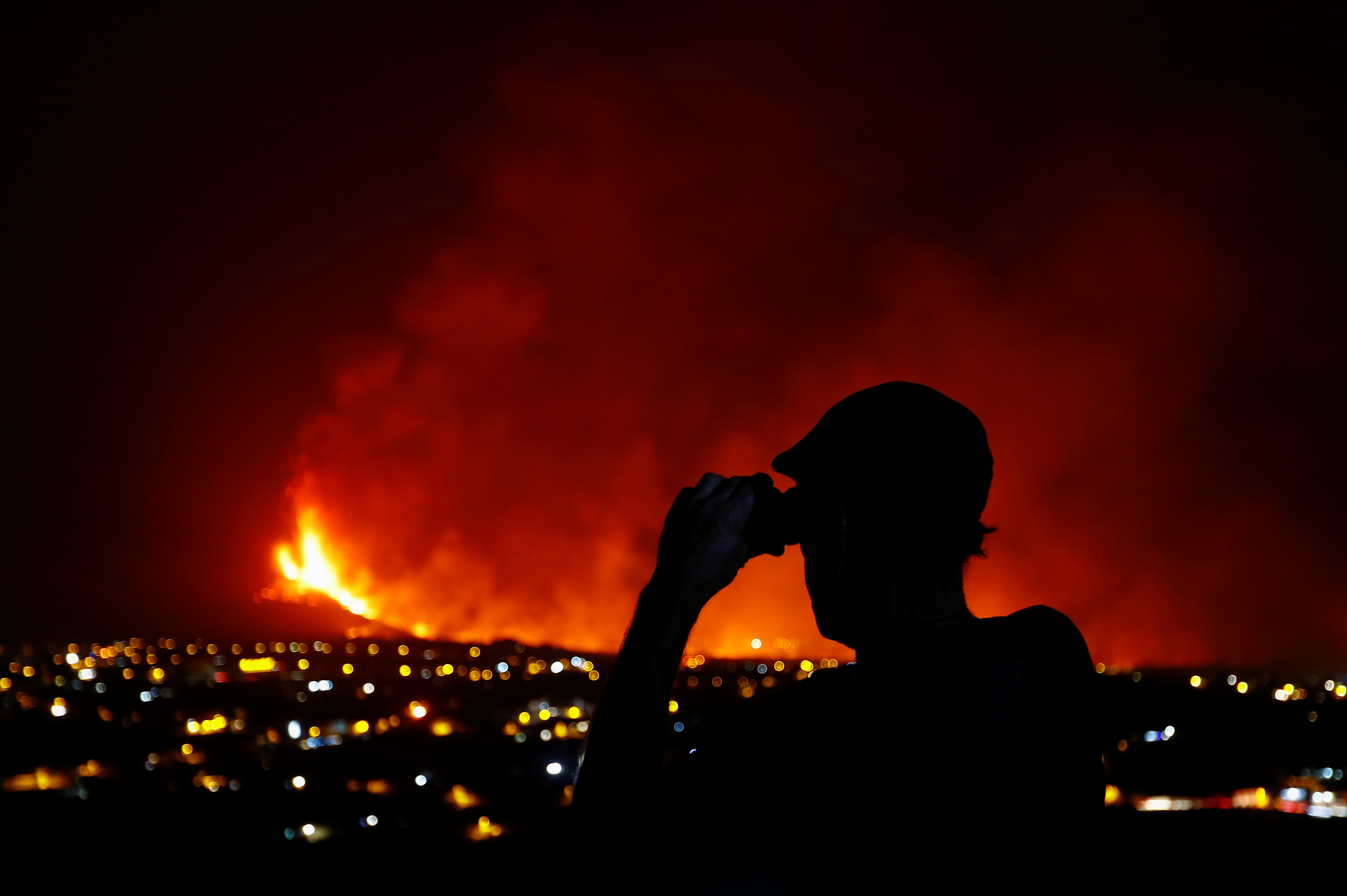 Roberto Diaz observes with binoculars the Cumbre Vieja volcano, in El Paso, on the Canary Island of La Palma, Spain, October 2, 2021. REUTERS/Borja Suarez