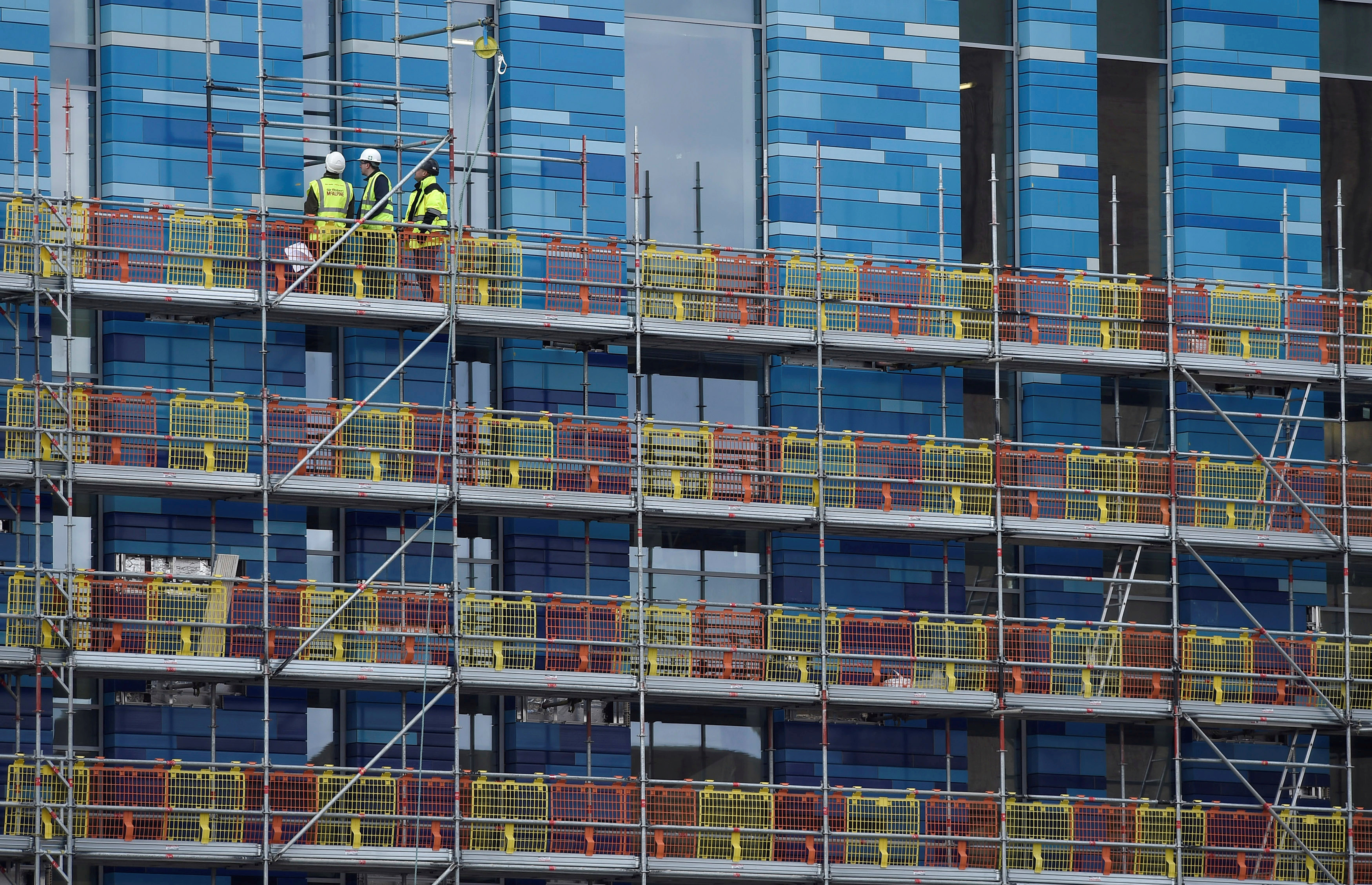 Workers stand on scaffolding at a residential building in London