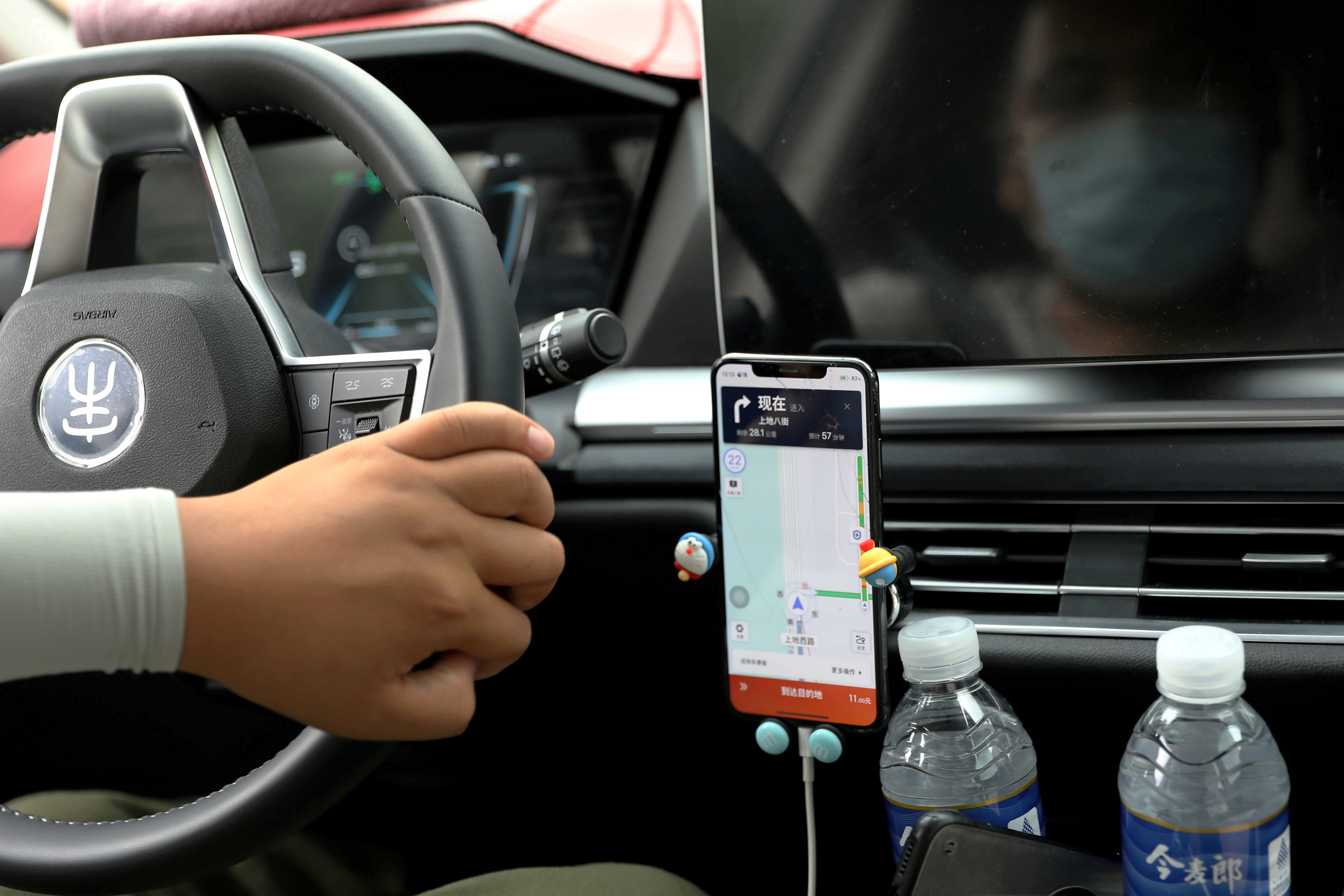 Driver of Chinese ride-hailing service Didi drives with a phone showing a navigation map on Didi's app, in Beijing