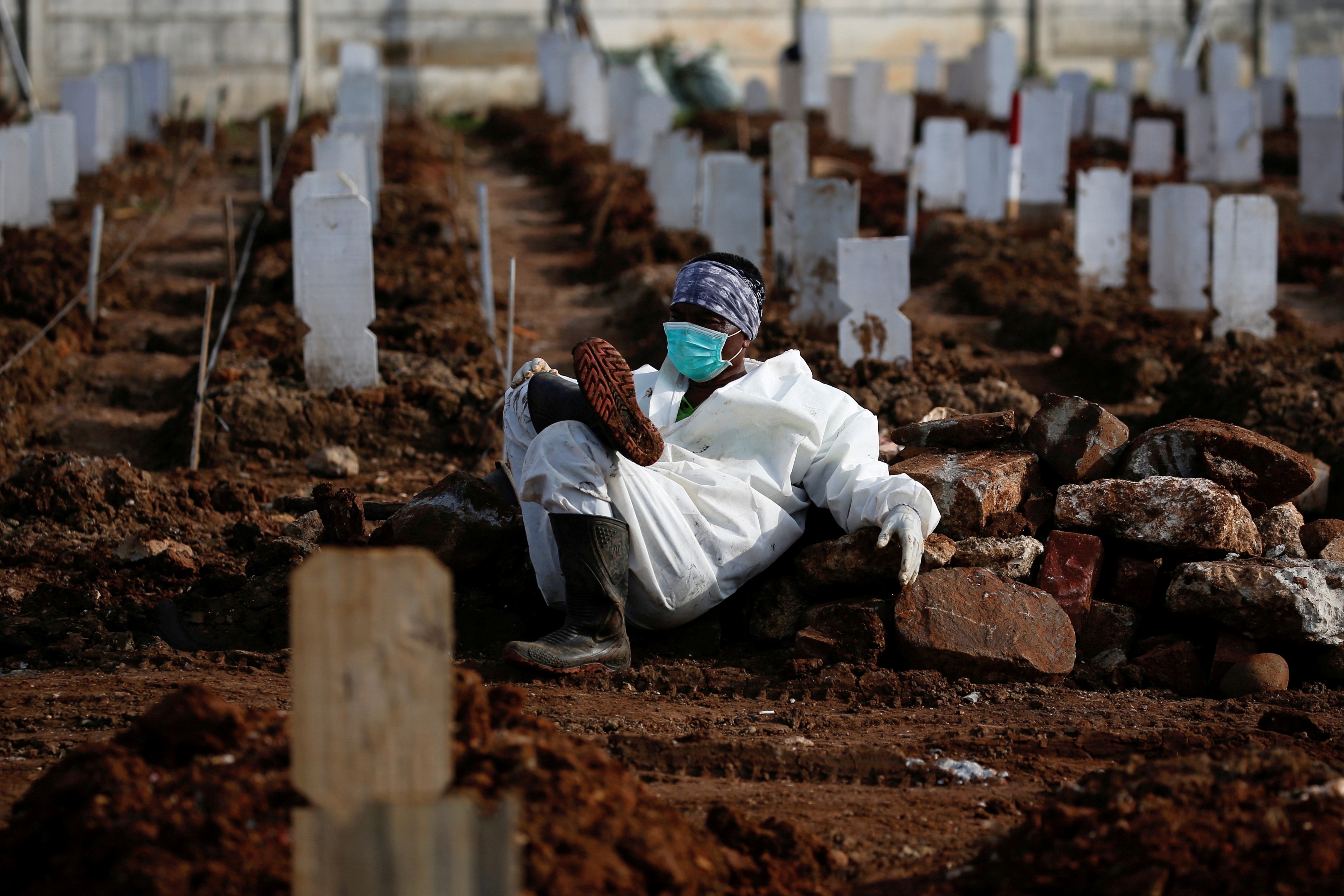 Municipality worker wearing PPE rests at the burial area provided by the government for COVID-19 victims in Jakarta
