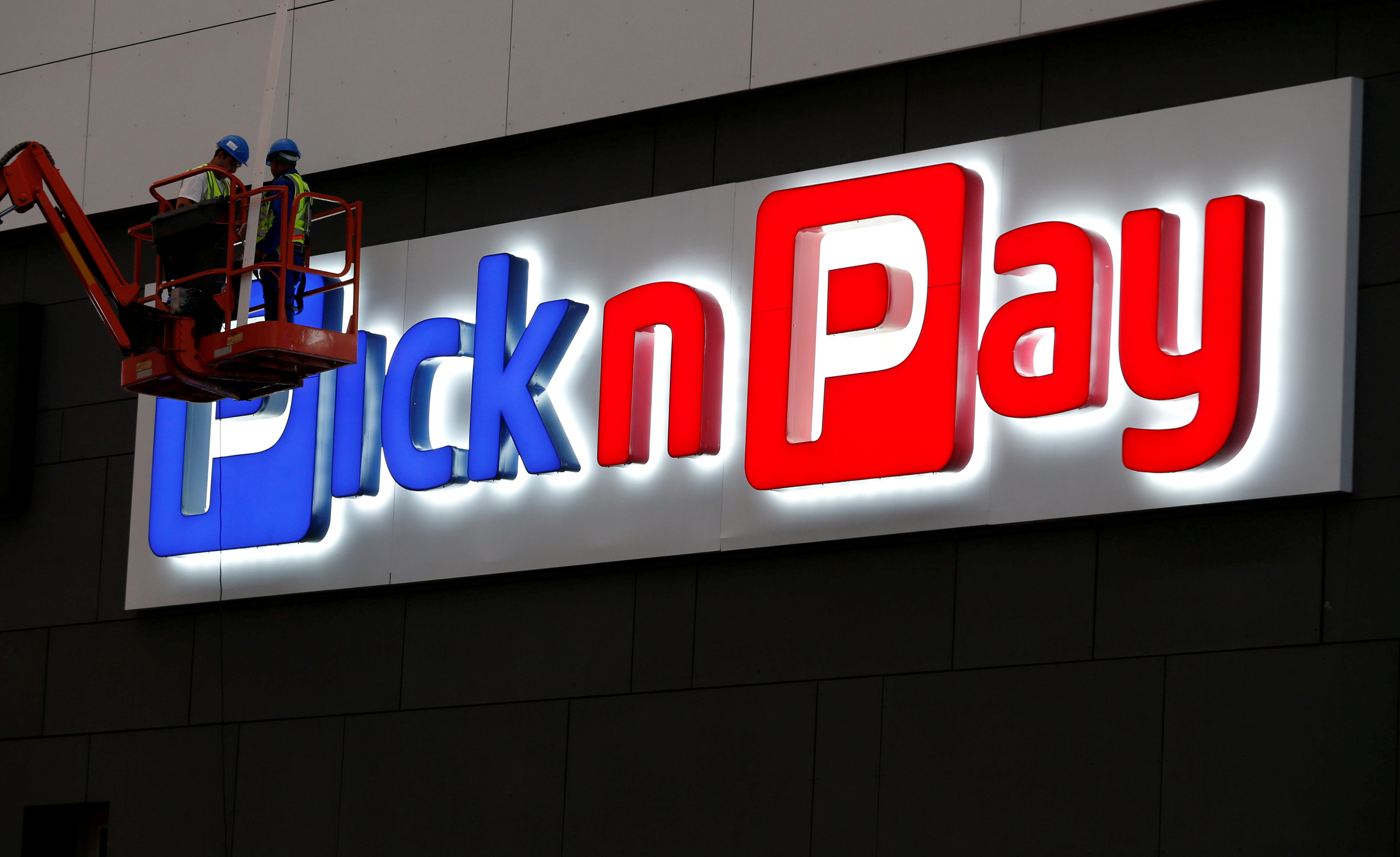 Workers repair a logo of South African retailer Pick n Pay in Johannesburg