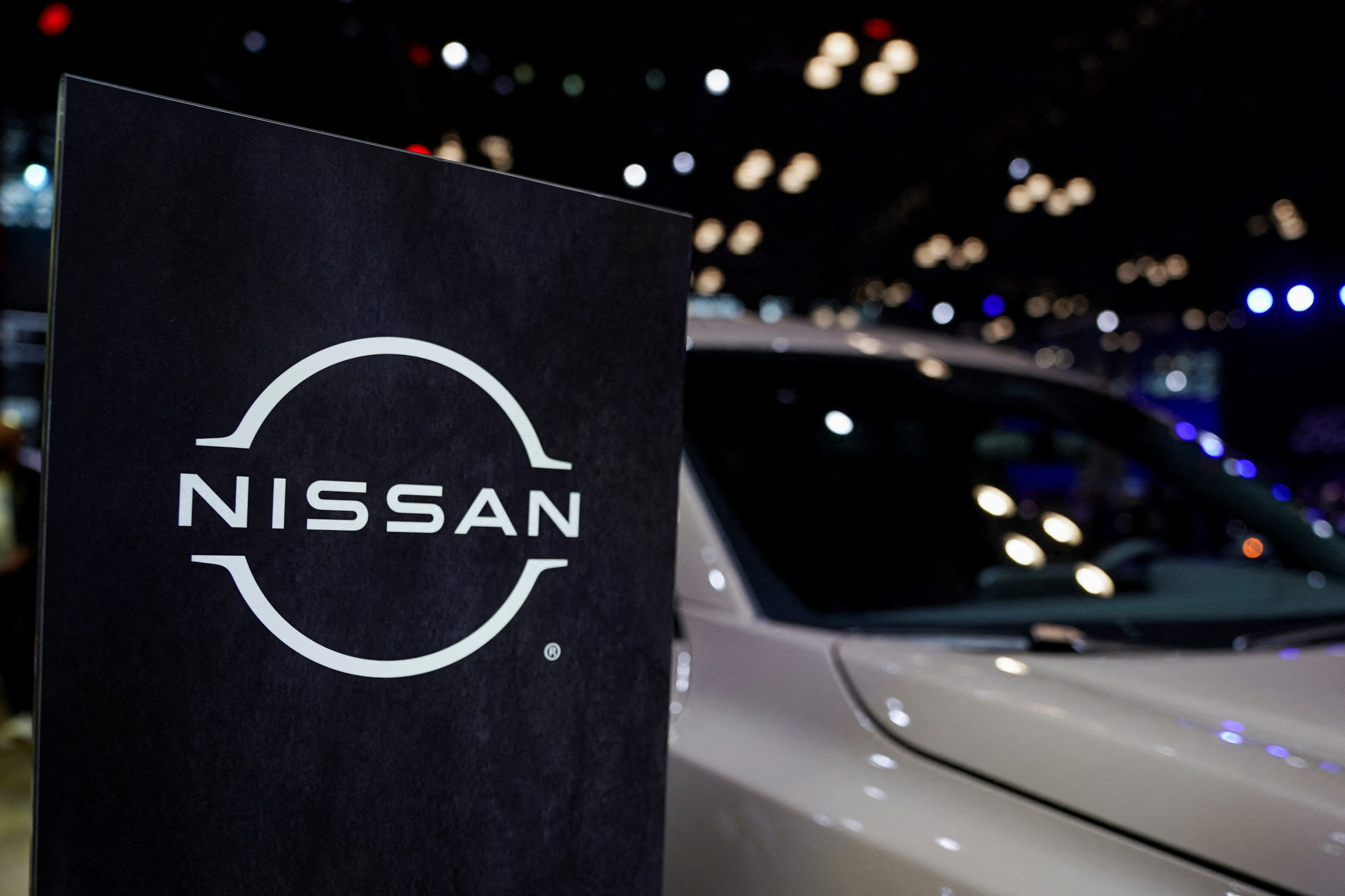 A Nissan logo is seen next to a vehicle during the New York International Auto Show