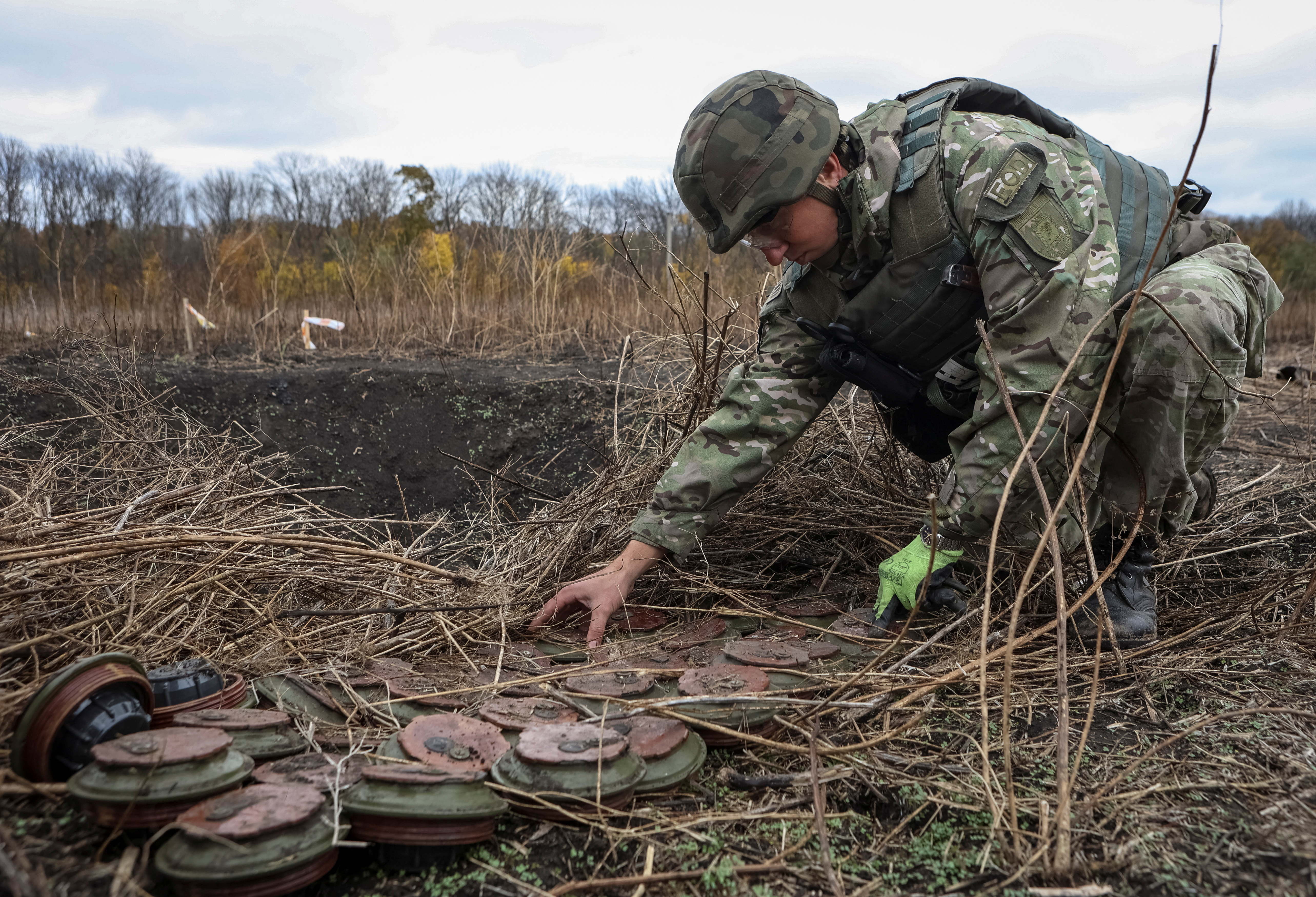 A member of the National police special demining unit works with mine fuses during a demining operation near Izum