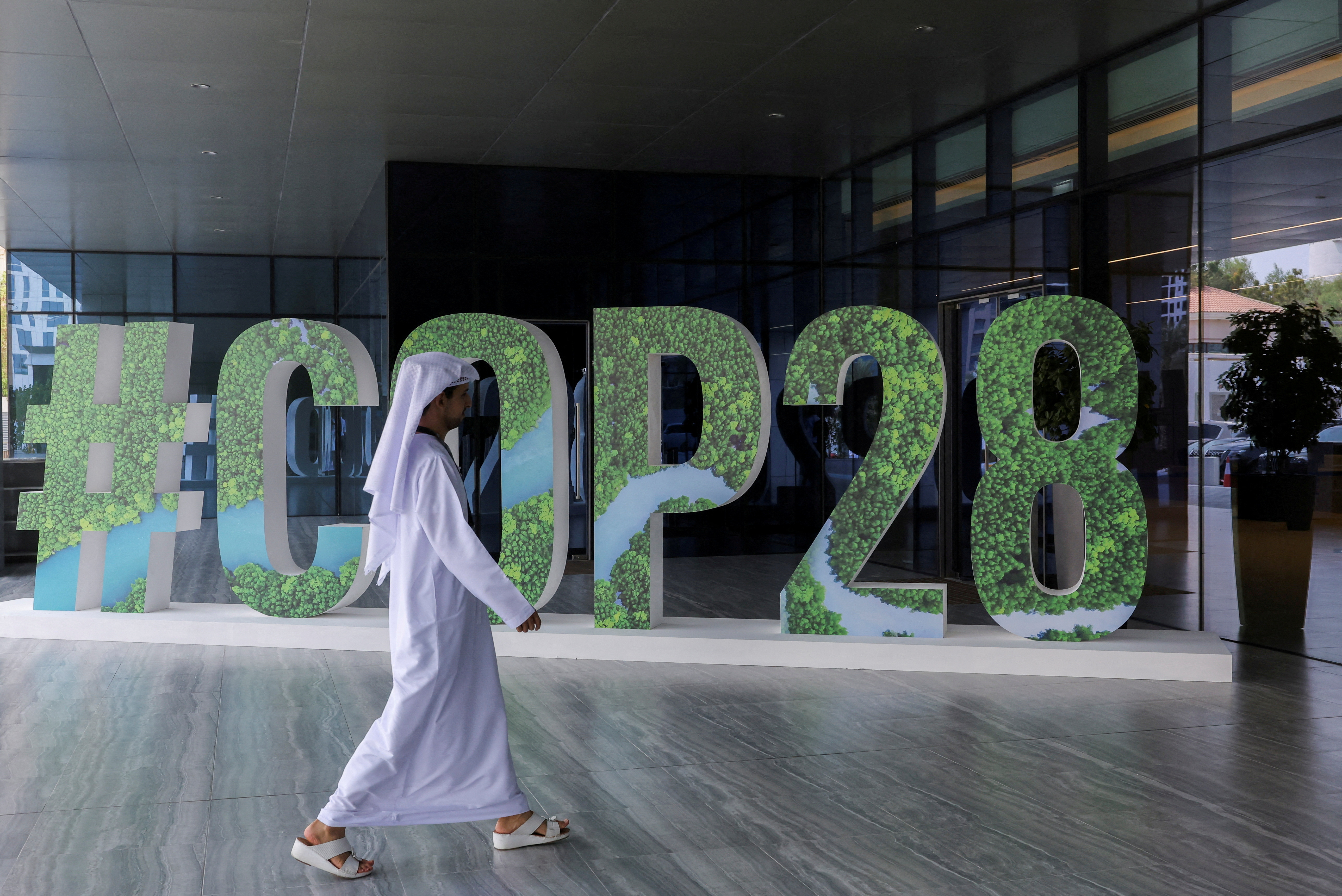 A person walks past a "#COP28" sign during The Changemaker Majlis, a one-day CEO-level thought leadership workshop focused on climate action, in Abu Dhabi