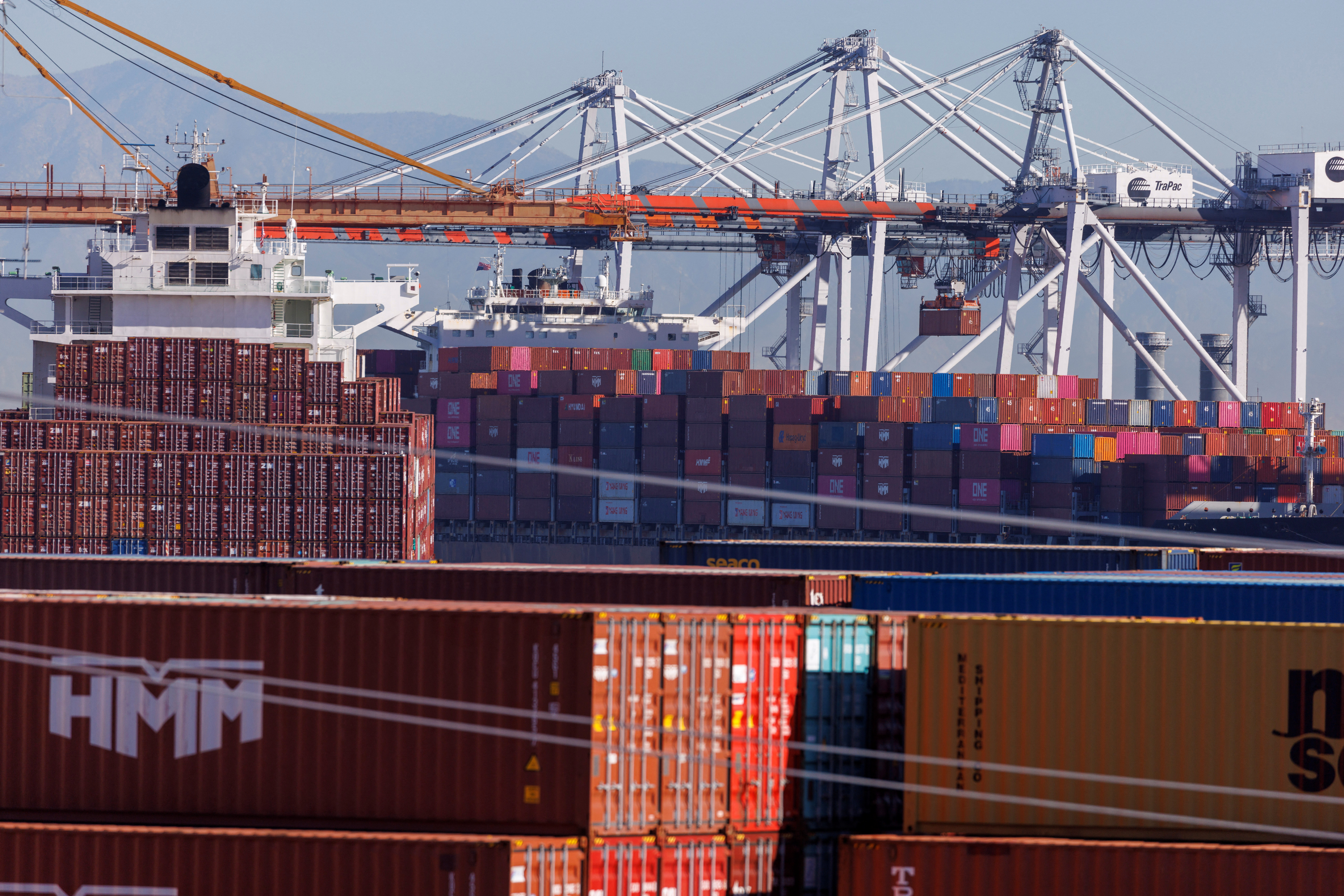 Stacked containers are shown as ships unload their cargo at the Port of Los Angeles