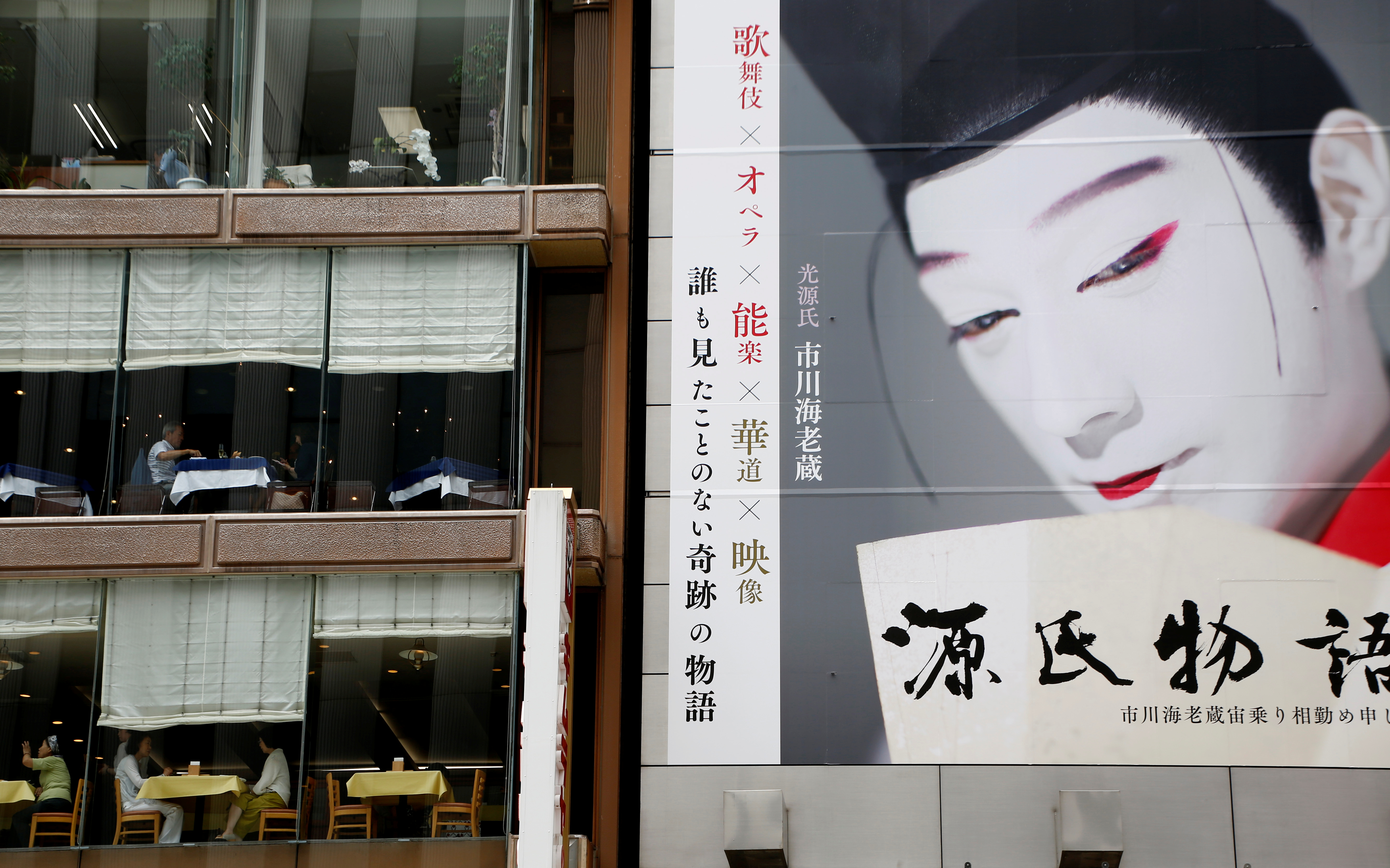Customers have lunch at restaurants next to a record shop which has a large poster on its wall in Tokyo, Japan
