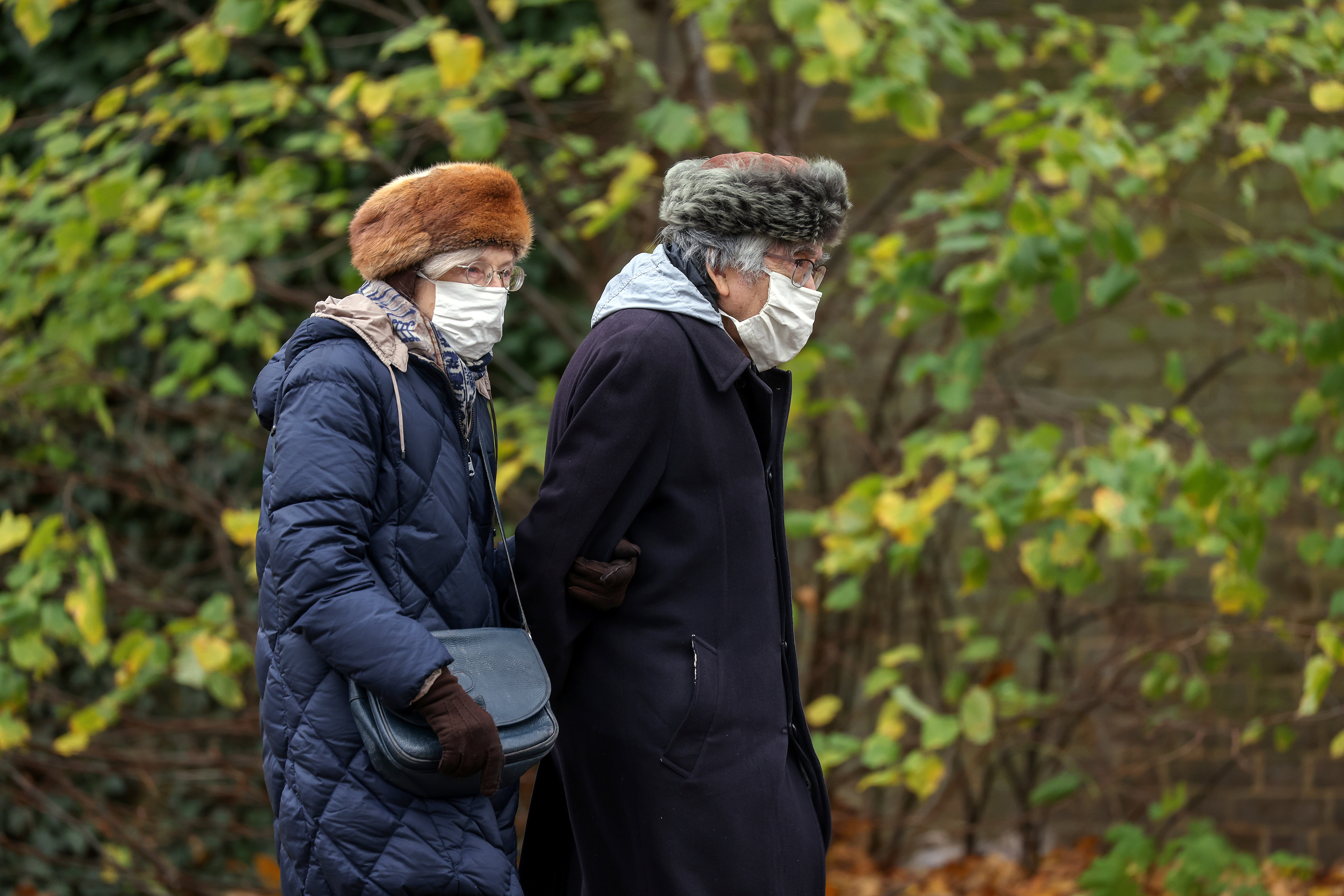 Pensioners wearing face masks and winter hats walk during lockdown in London