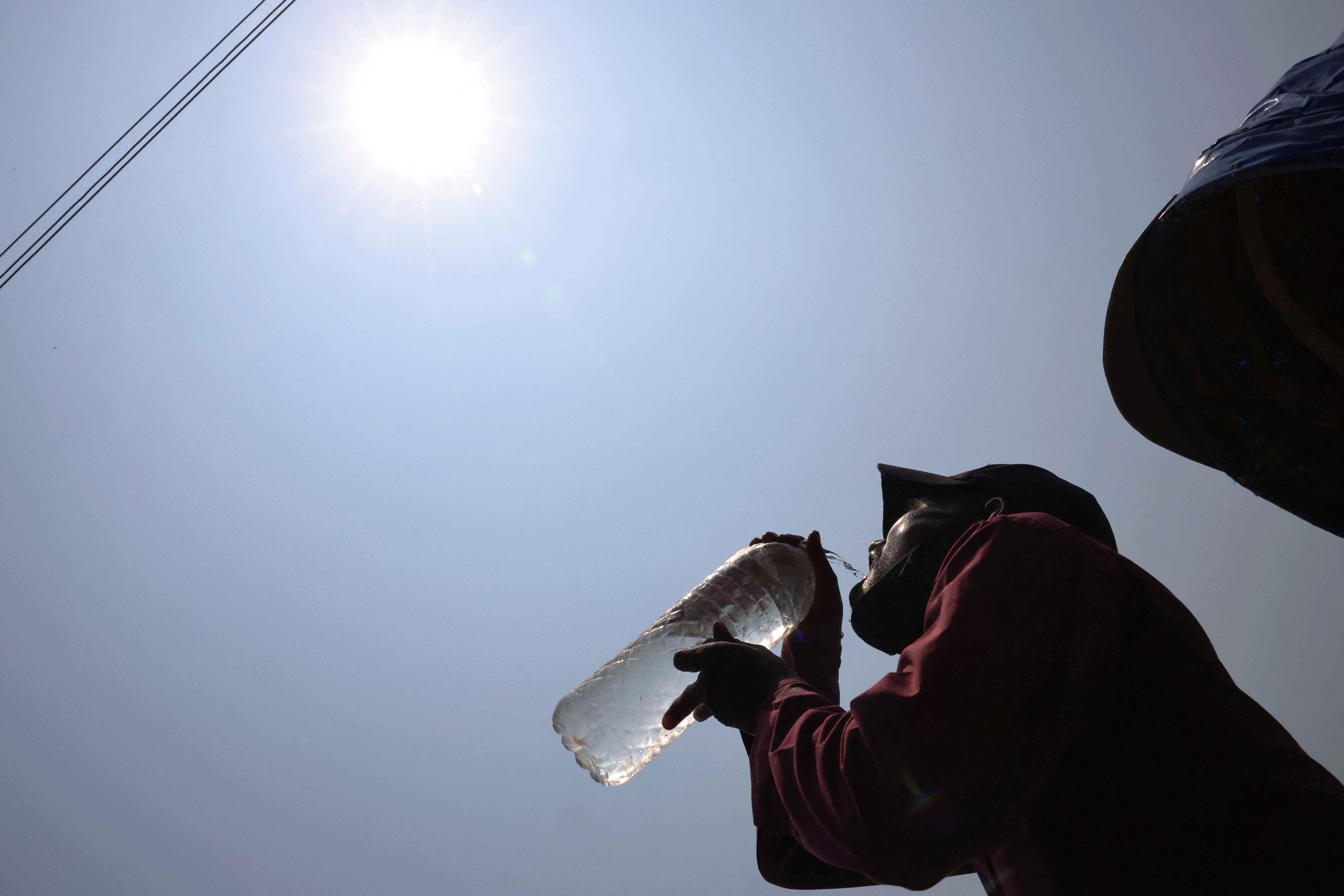 A man drinks cold water at noon during a heatwave in Dhaka