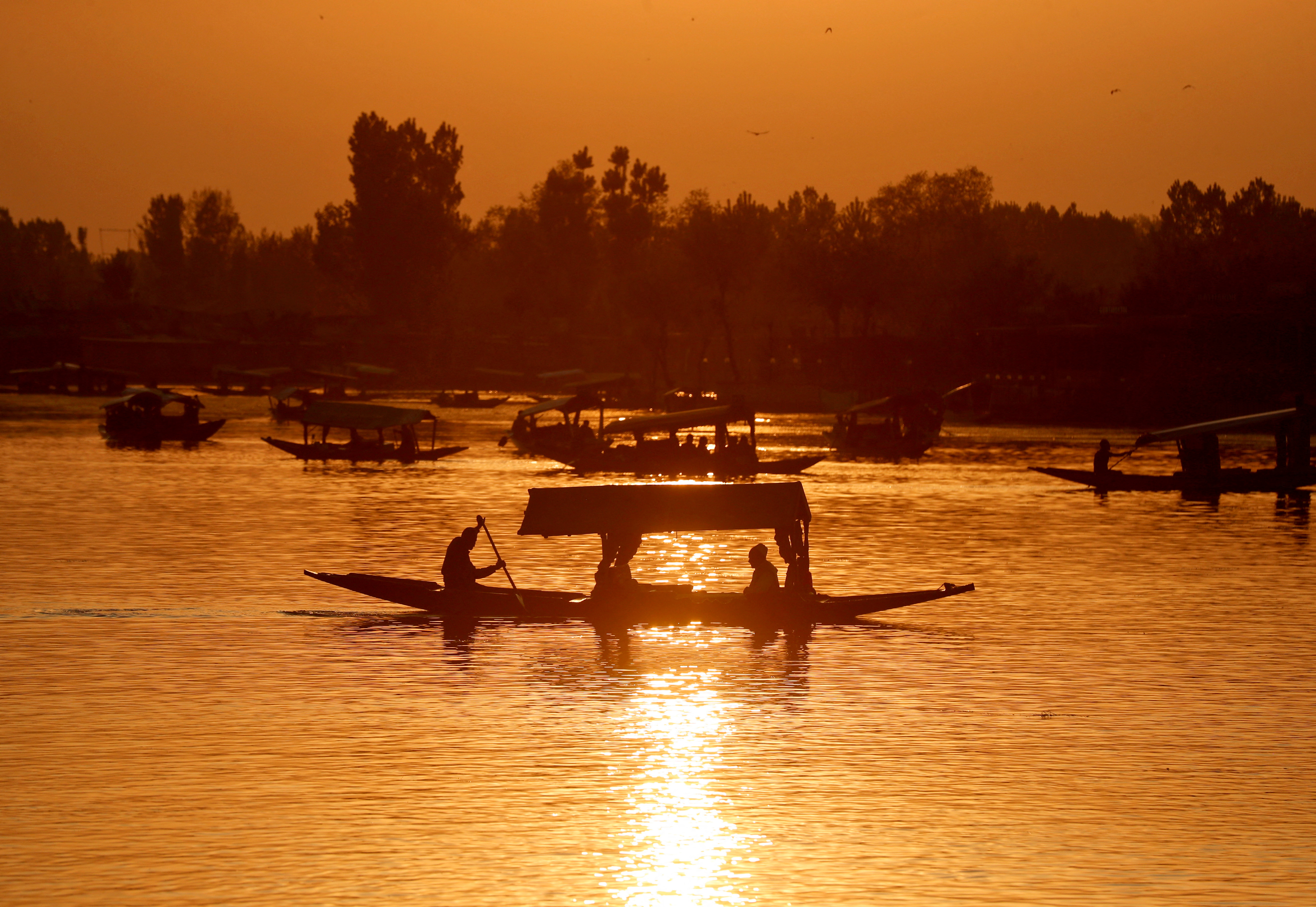 Tourists ride "Shikaras" or boats in the waters of Dal Lake during sunset in Srinagar