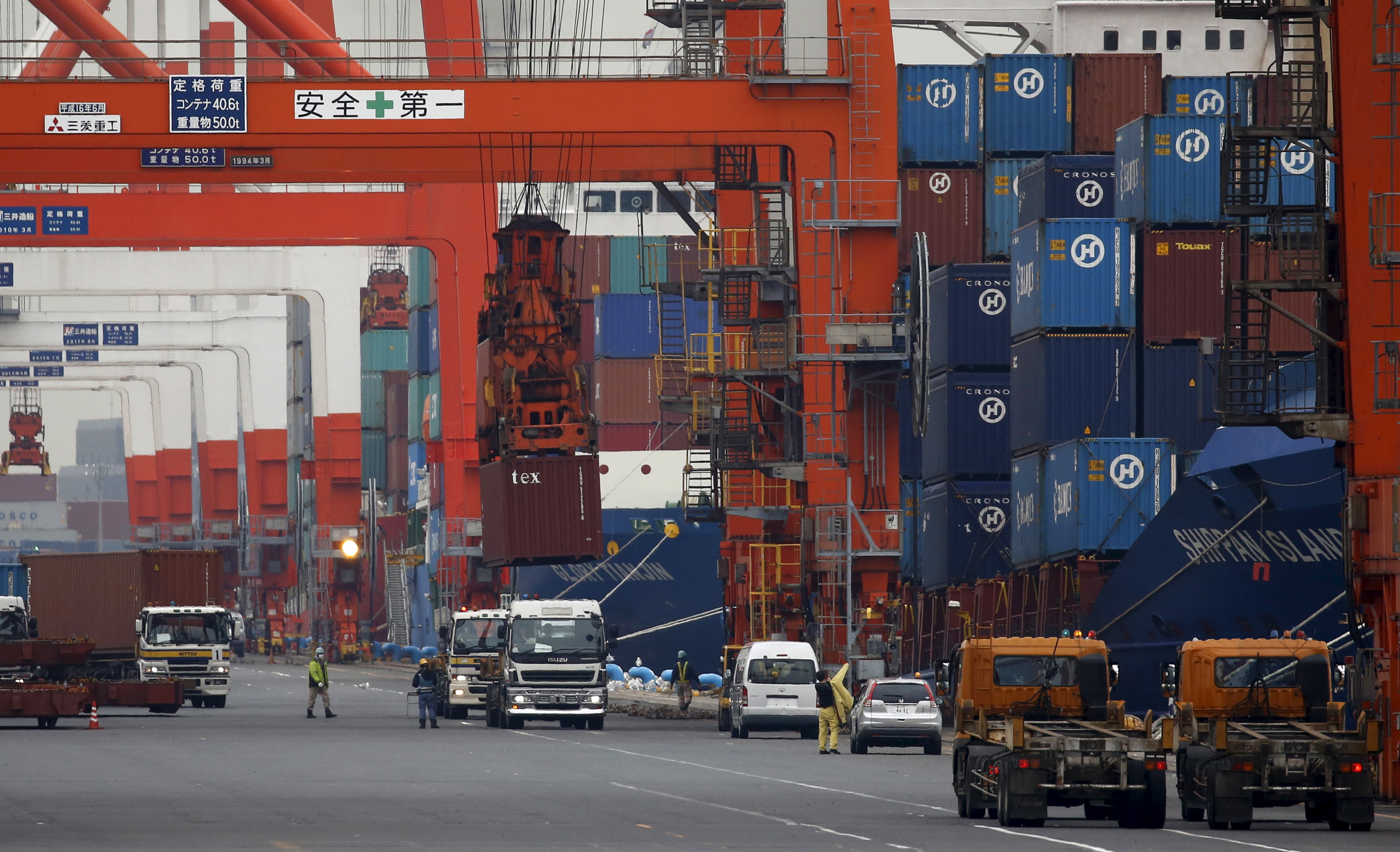 Workers load containers onto trucks from a cargo ship at a port in Tokyo