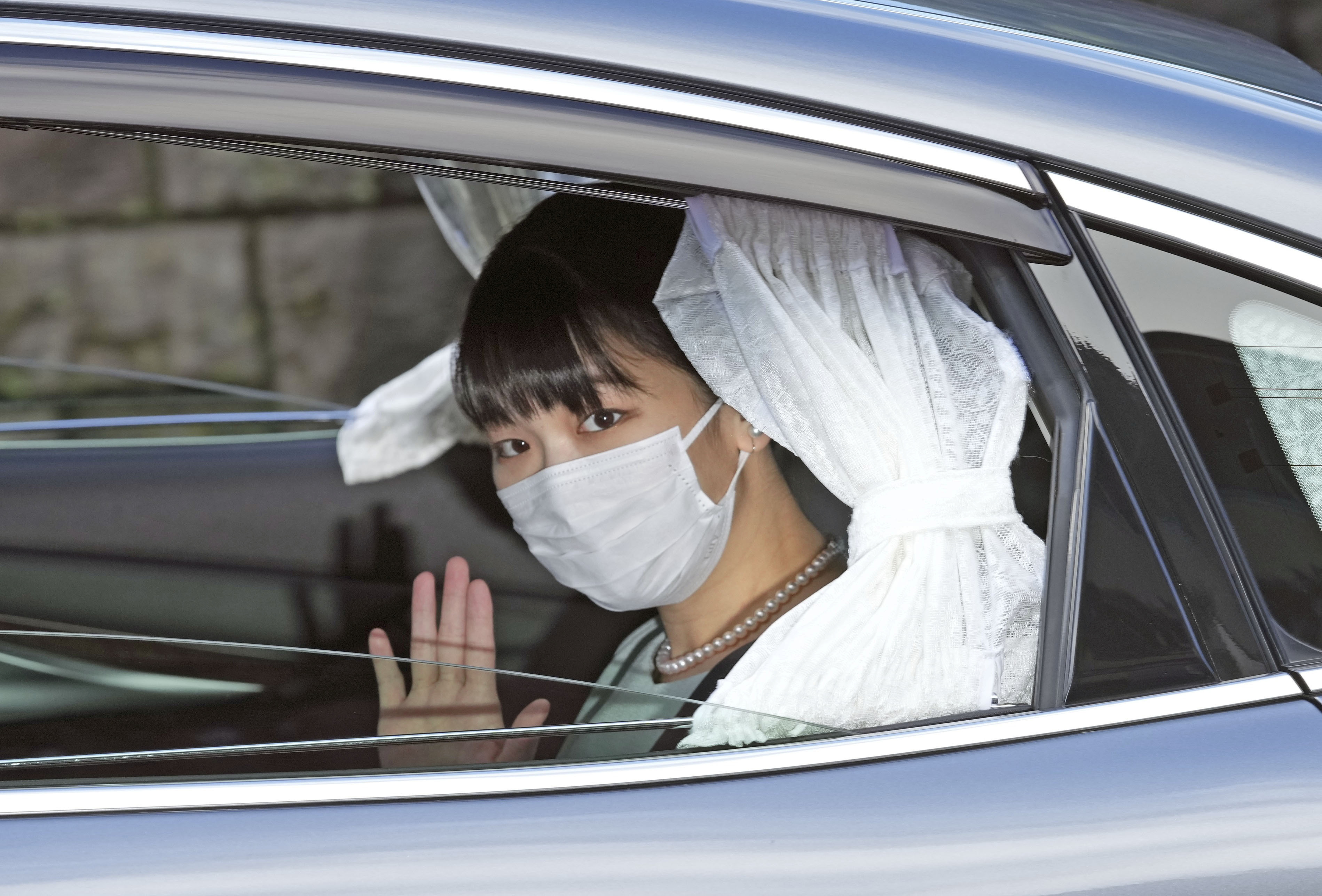 Japan's Princess Mako waves from inside a car as she leaves her home for her marriage in Akasaka Estate in Tokyo, Japan October 26, 2021 in this photo taken by Kyodo. Kyodo/via REUTERS  
