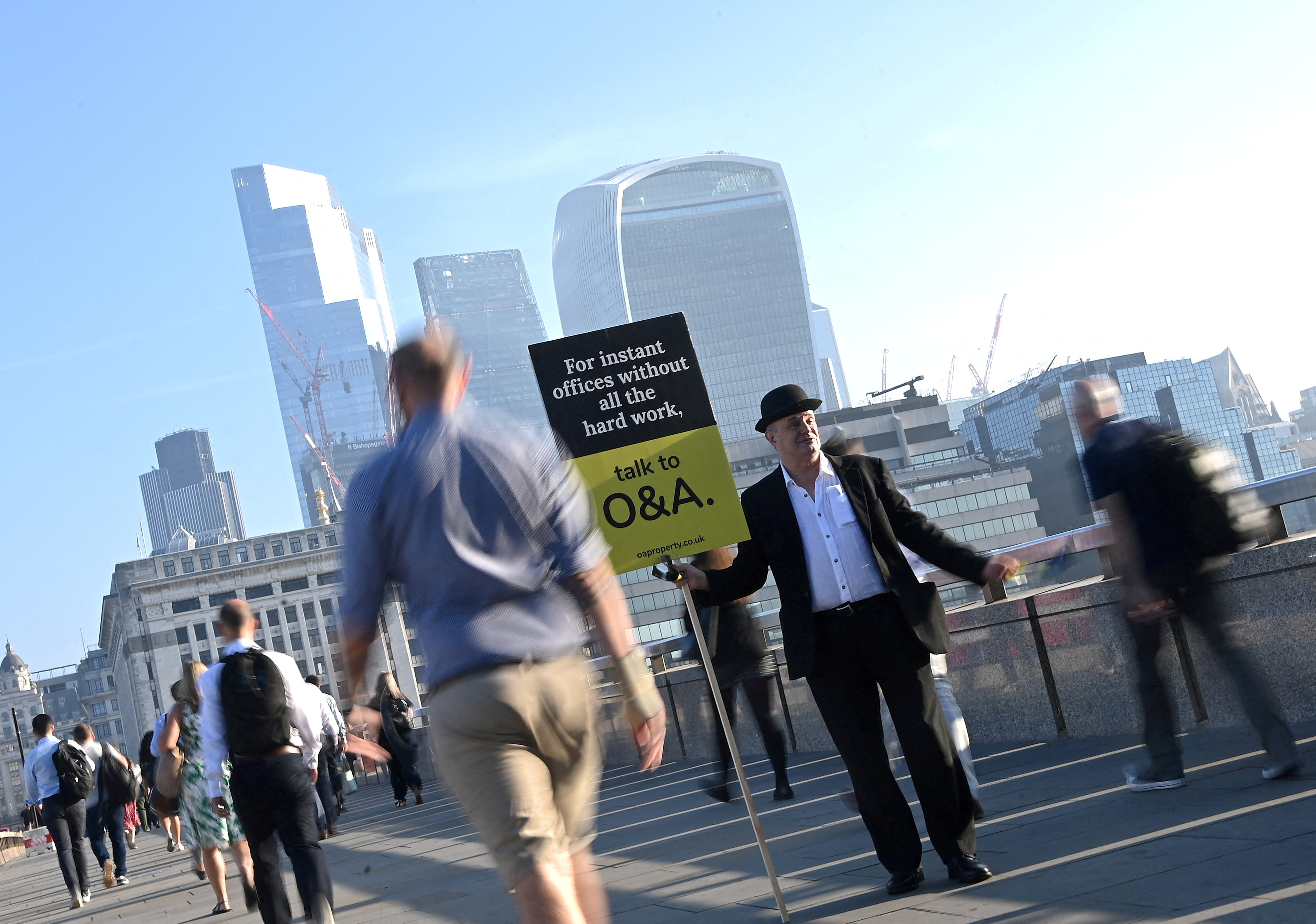 FILE PHOTO: Workers walk towards the City of London financial district as they cross London Bridge during the morning rush hour in London