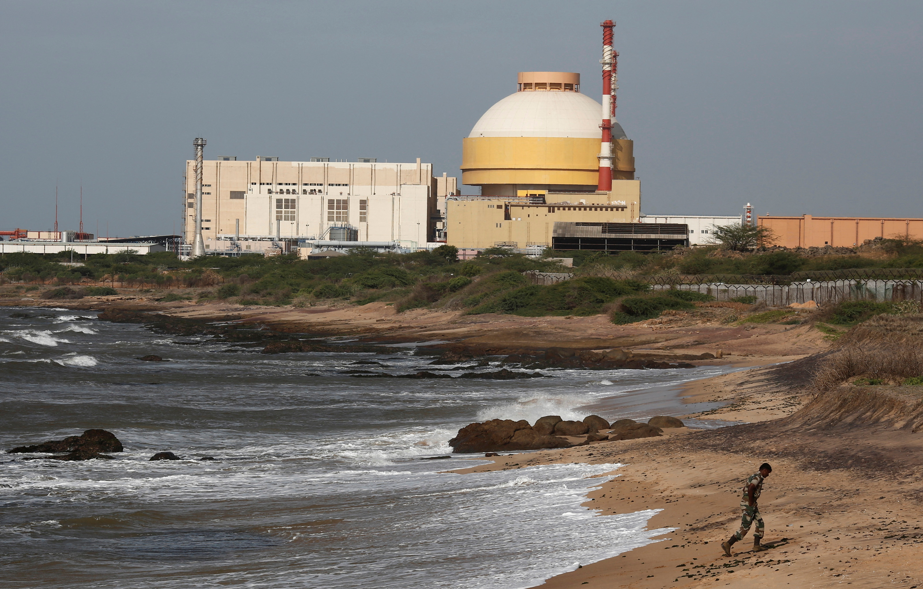 A policeman walks on a beach near Kudankulam nuclear power project