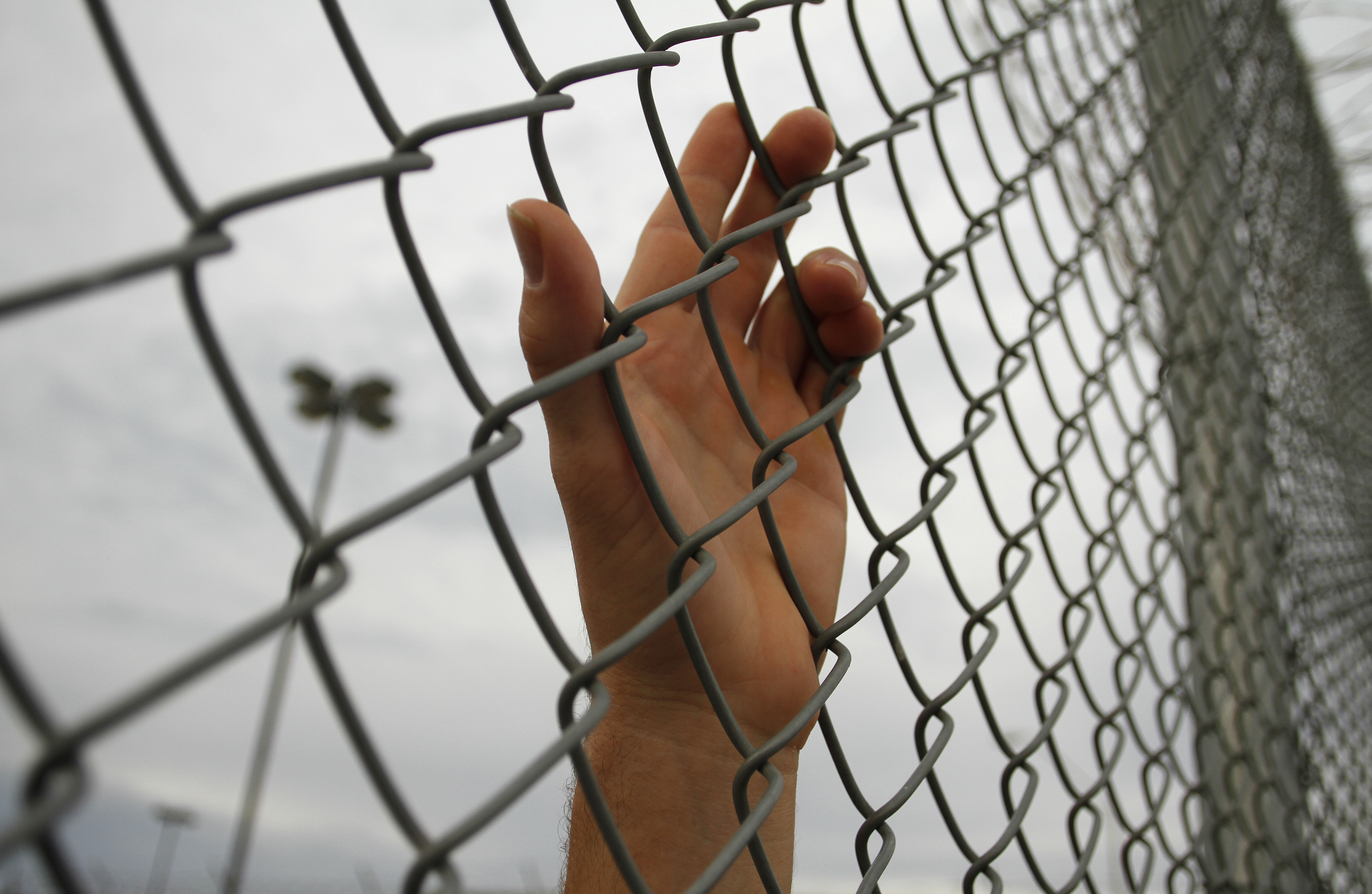 An inmate serving a jail sentence rests his hand on a fence at Maricopa County's Tent City jail in Phoenix