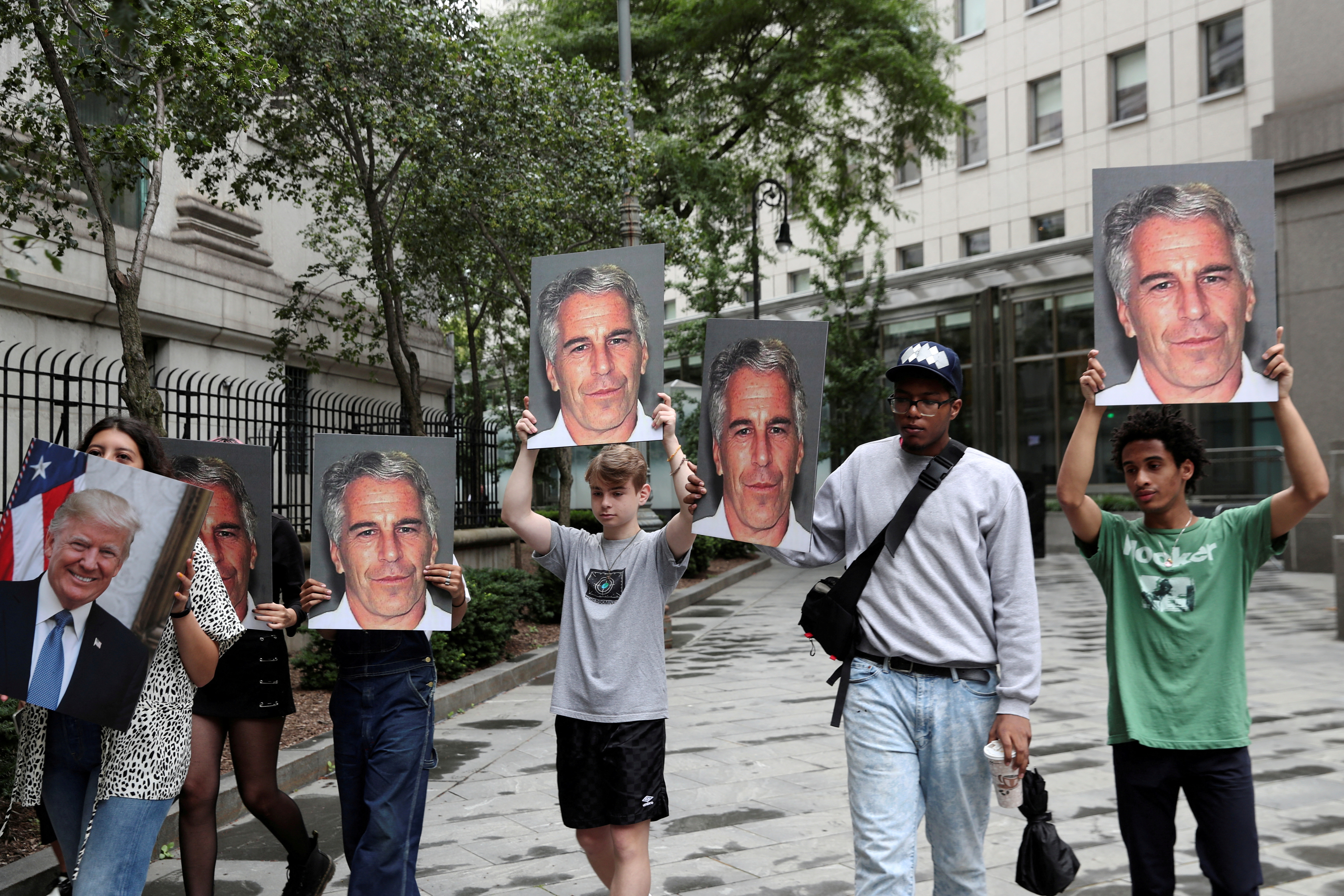 Demonstrators hold photos aloft protesting Jeffrey Epstein in New York