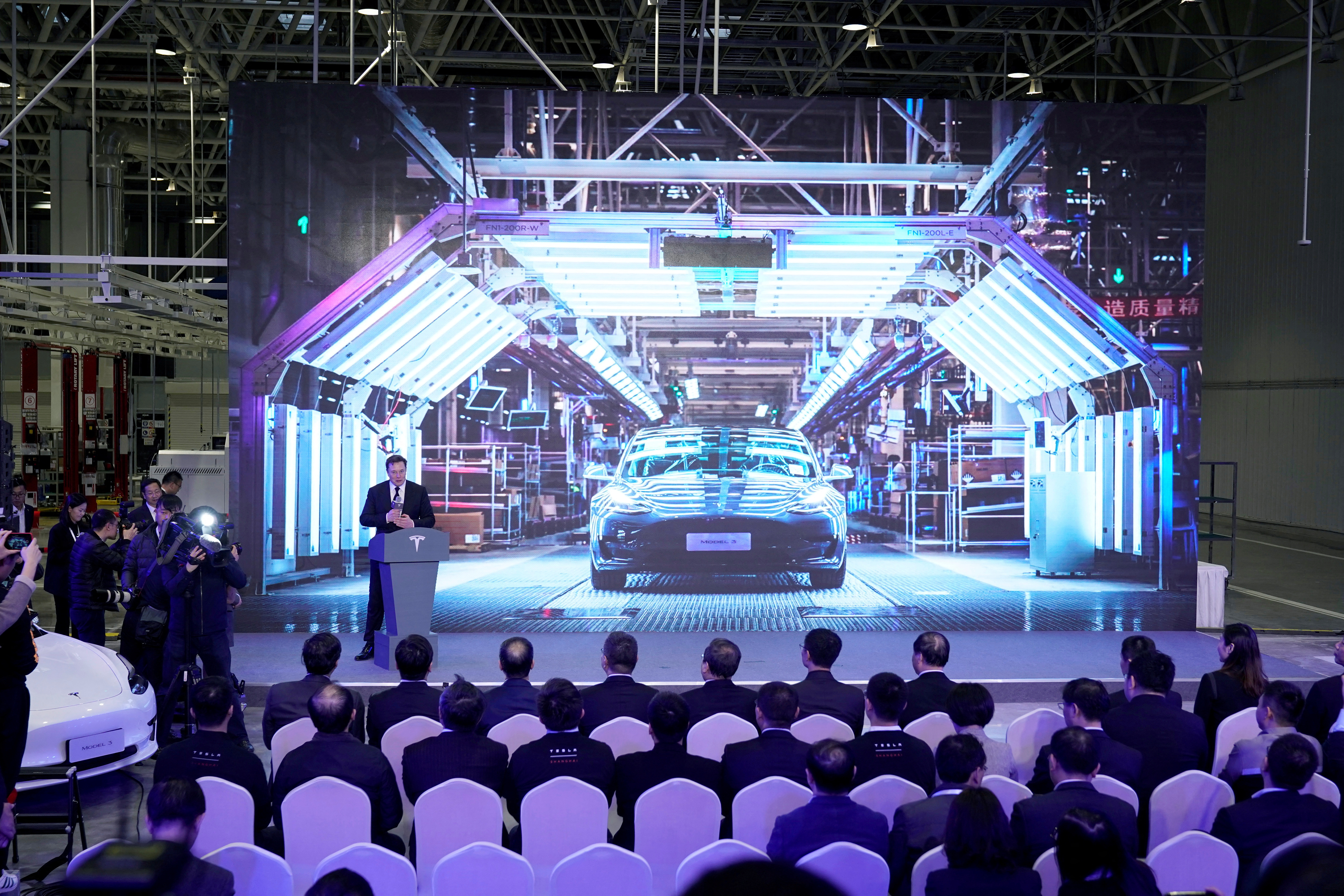 Tesla Inc CEO Elon Musk speaks next to a screen showing an image of Tesla Model 3 car during an opening ceremony for Tesla China-made Model Y program in Shanghai