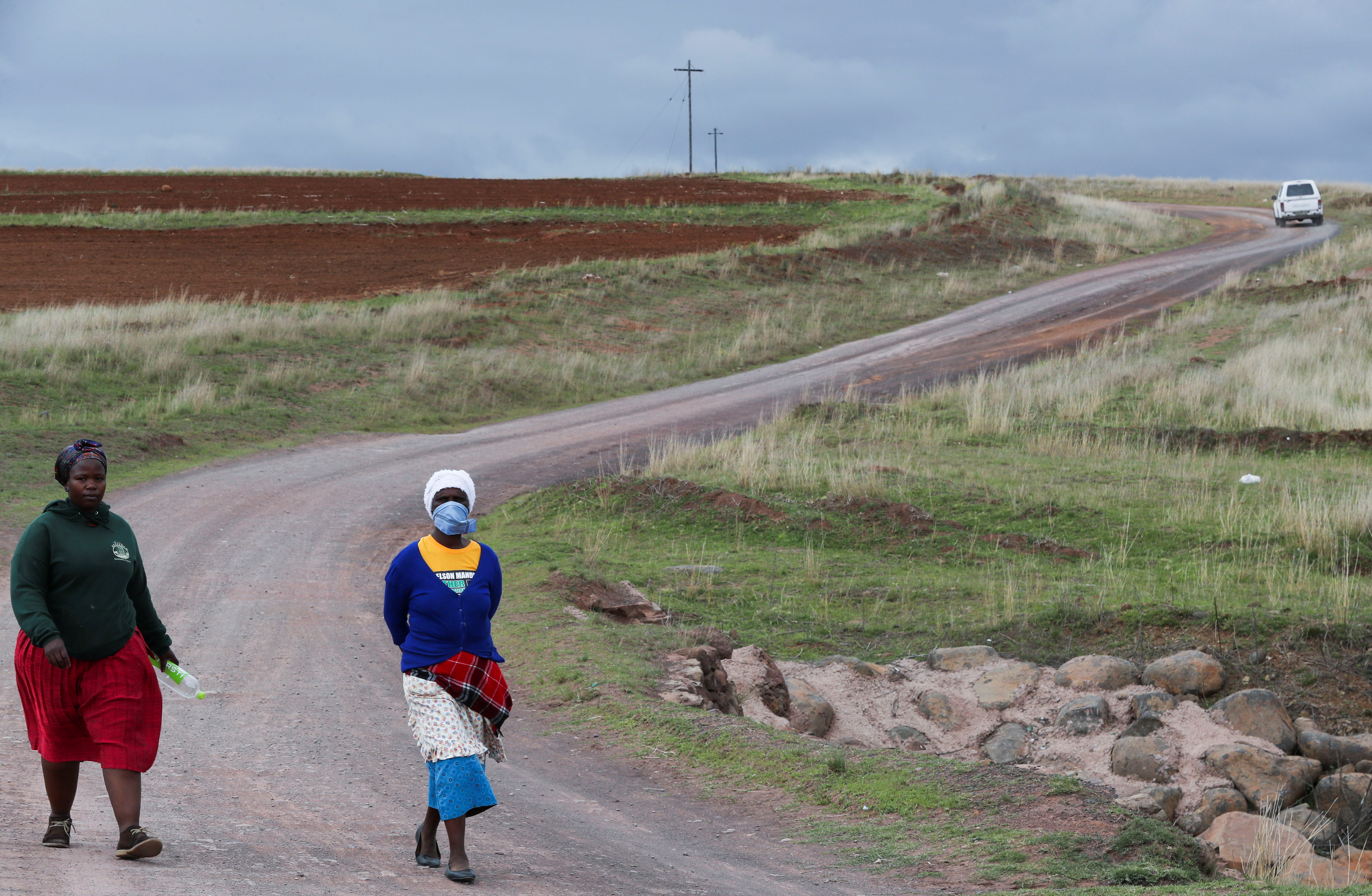 Women walk on a dirt road while using a handkerchief to cover their nose, as the new coronavirus variant, Omicron spreads, in Qumanco village in the Eastern Cape province of South Africa, November 30, 2021. REUTERS/Siphiwe Sibeko