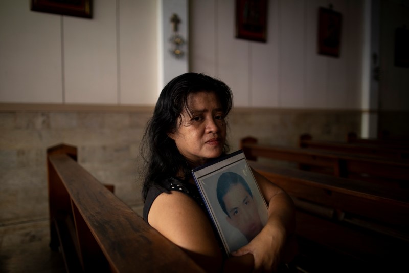 Normita Lopez, 56, is photographed while holding a portrait of her son Djastin Lopez, in a church nearby her home in Manila