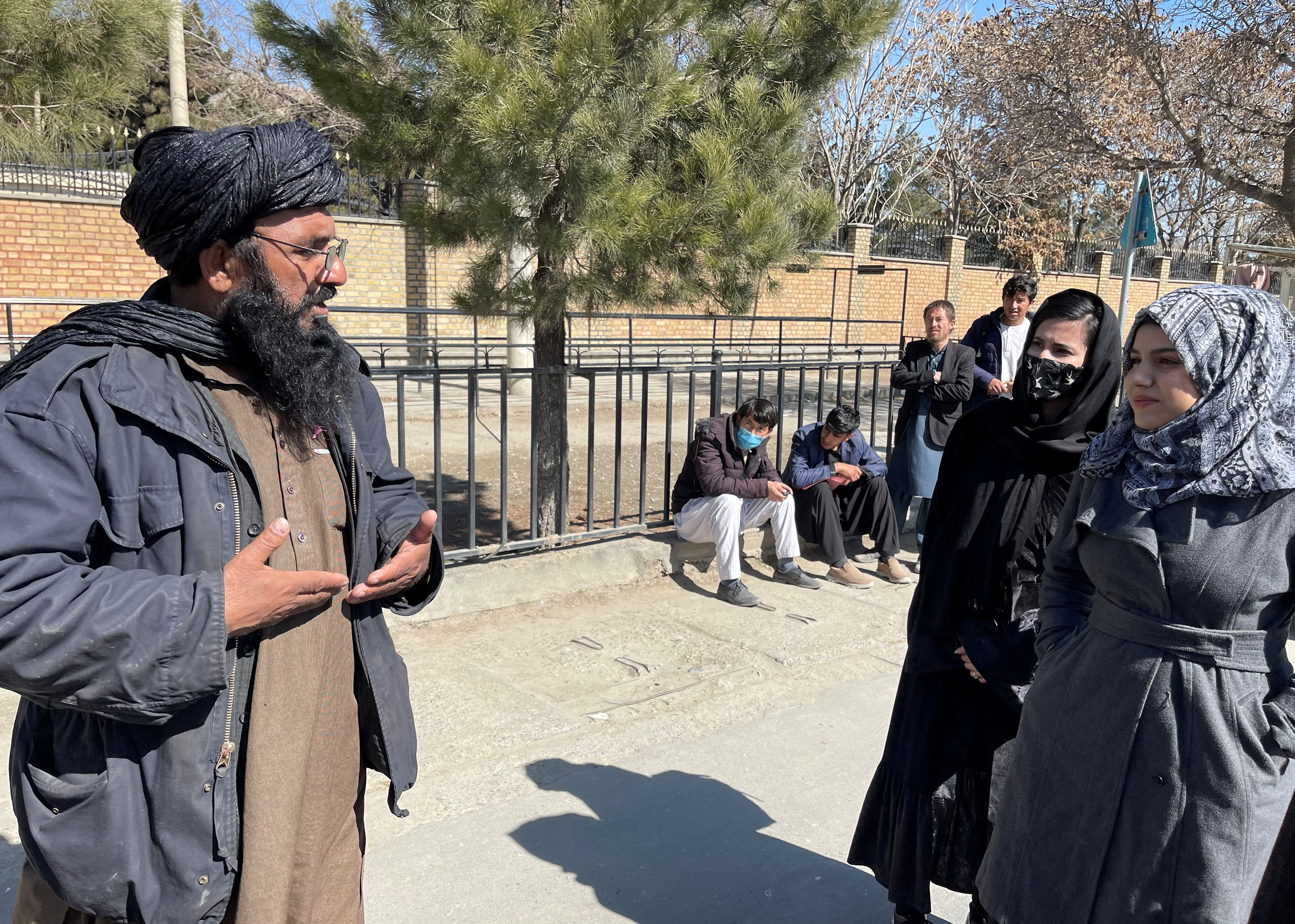 A member of Taliban speaks with female students outside the Kabul Education University in Kabul