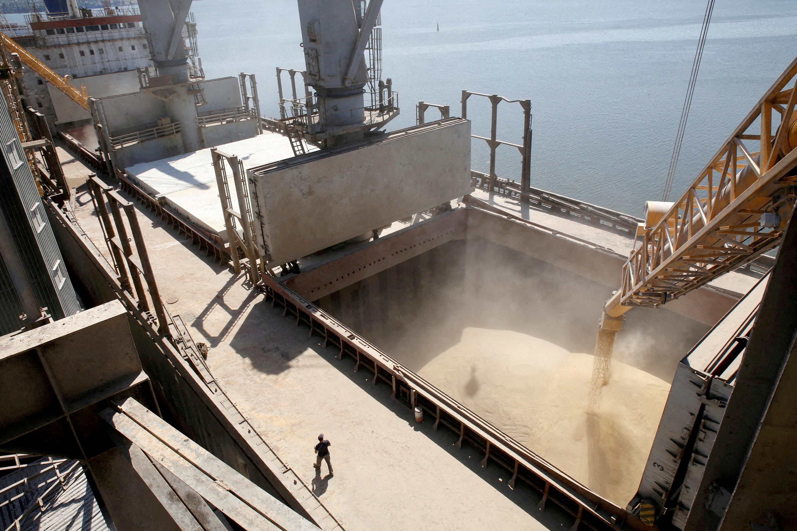 A dockyard worker watches as barley grain is poured into a ship in Nikolaev