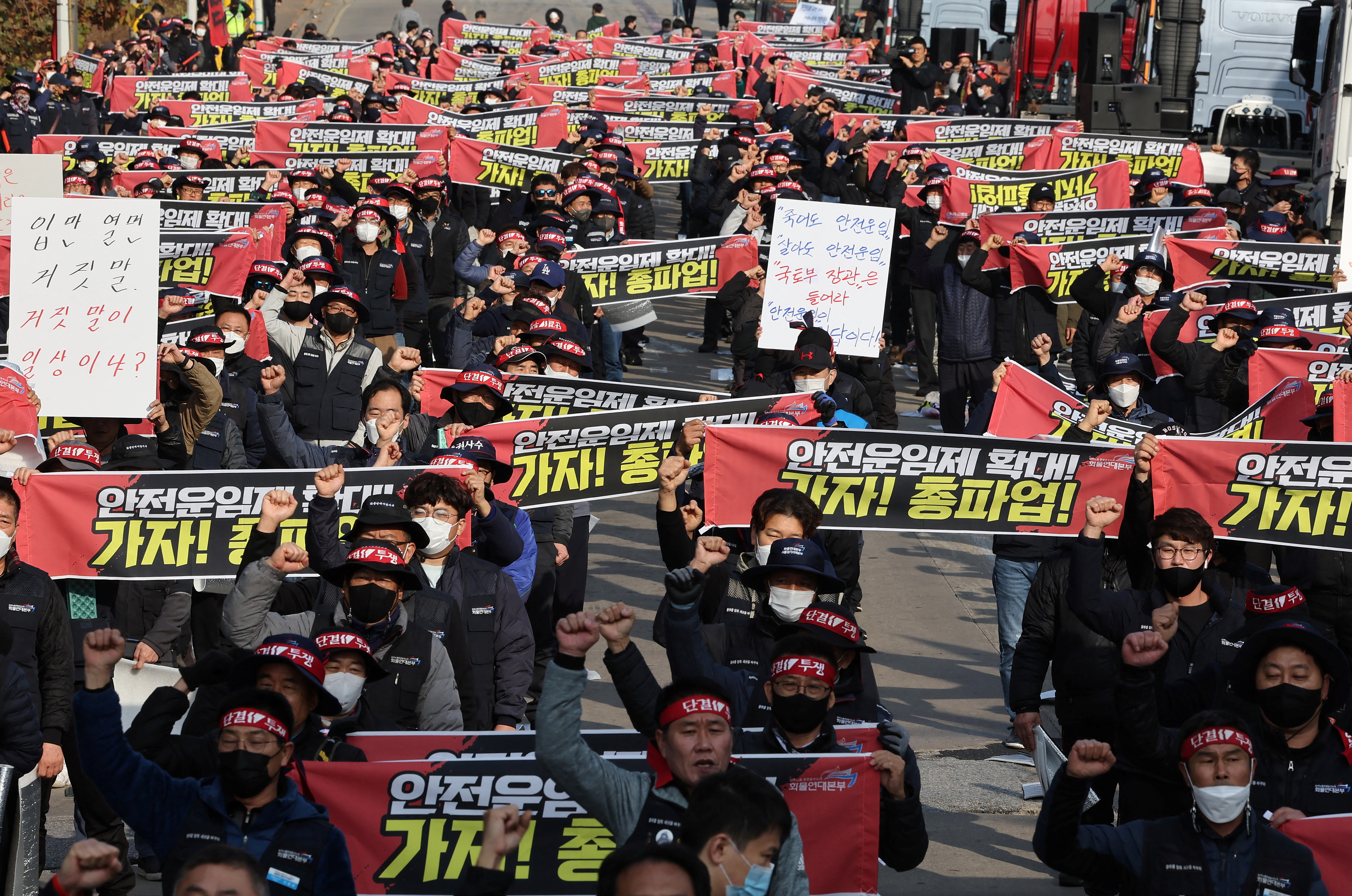 Unionized truckers shout slogans during their rally as they kick off their strike in front of transport hub in Uiwang