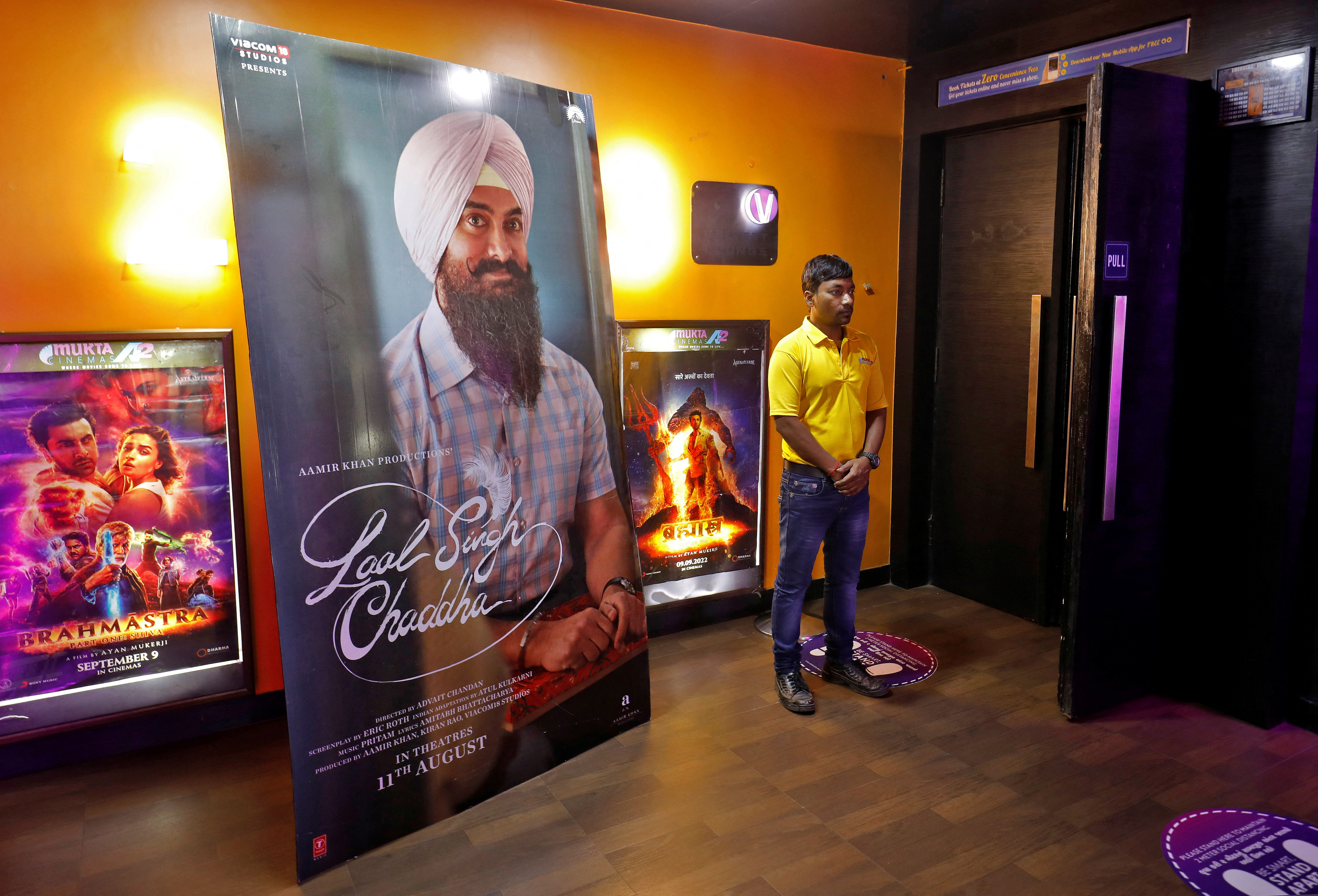 A ticket checker waits for film-goers at the gate of a cinema hall showcasing Aamir Khan-starrer 