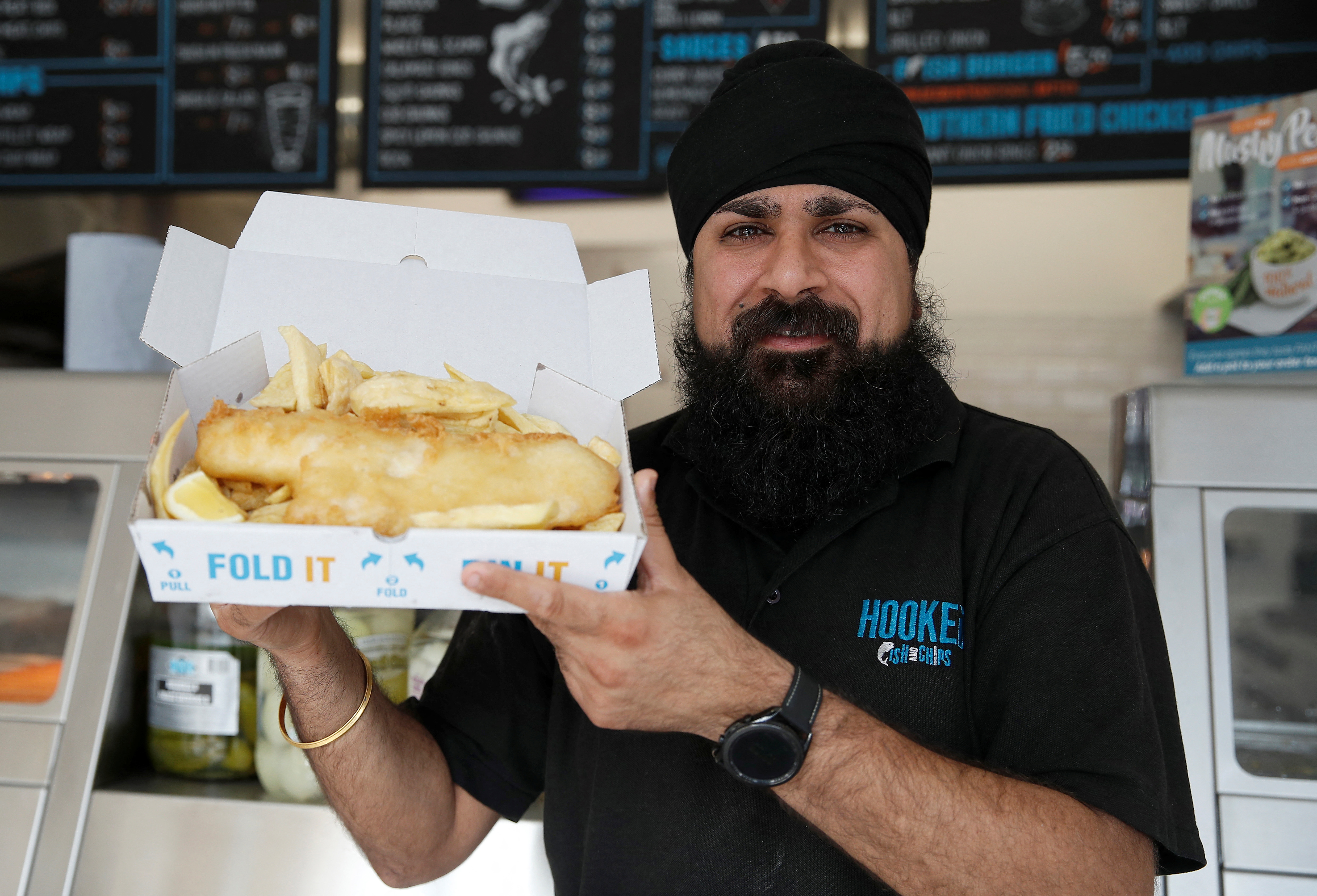 Owner of Hooked Fish and Chips shop, Bally Singh, holds a portion of fish and chips at his take-away in West Drayton