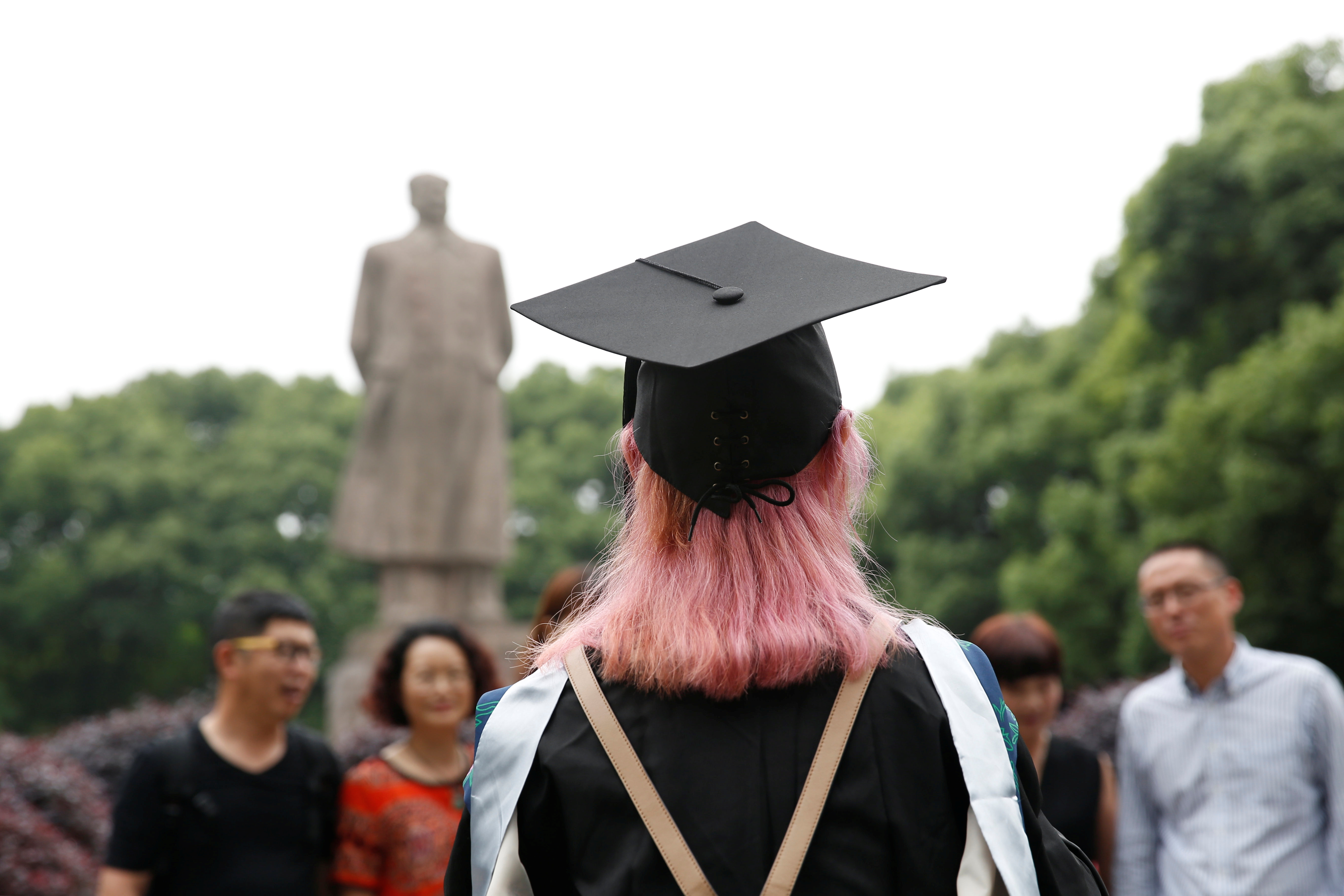 A student stands in front of the statue of Chinese leader Mao Zedong after her graduation ceremony at Fudan University in Shanghai