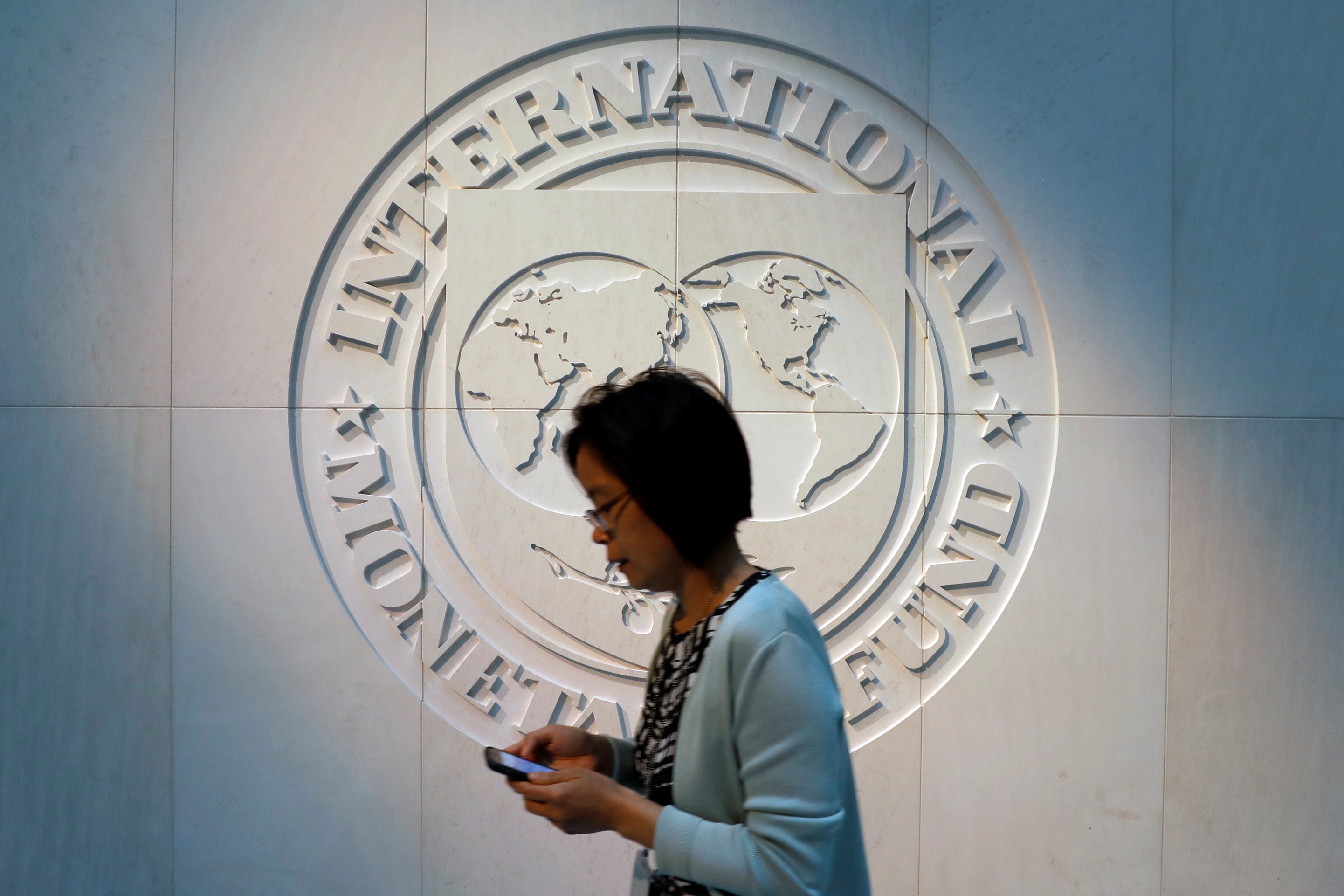 Woman walks past the IMF logo at HQ in Washington