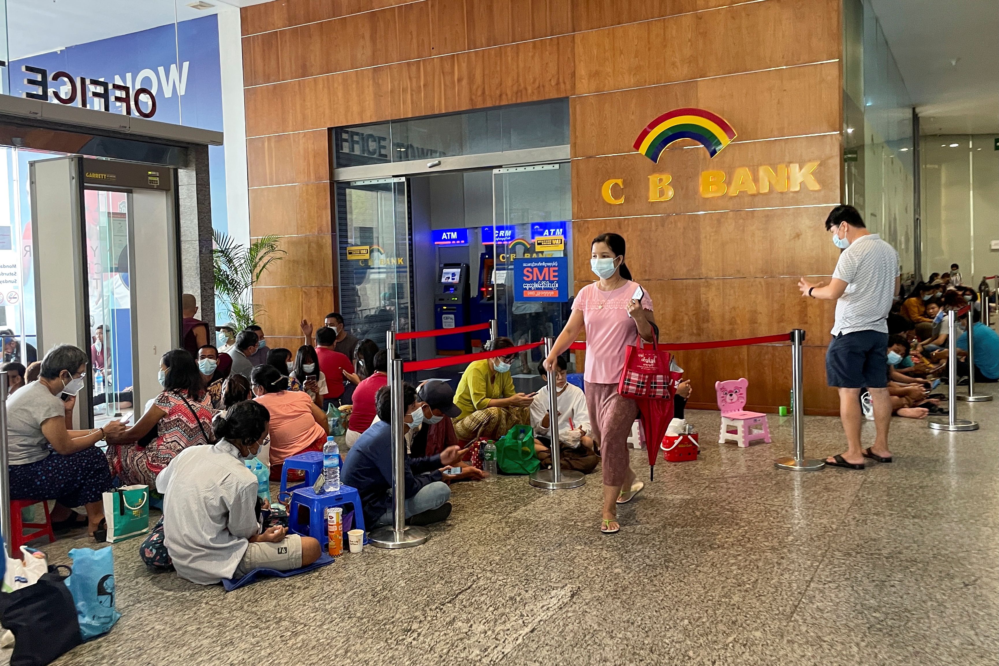 People line up outside a bank to withdraw cash, in Yangon