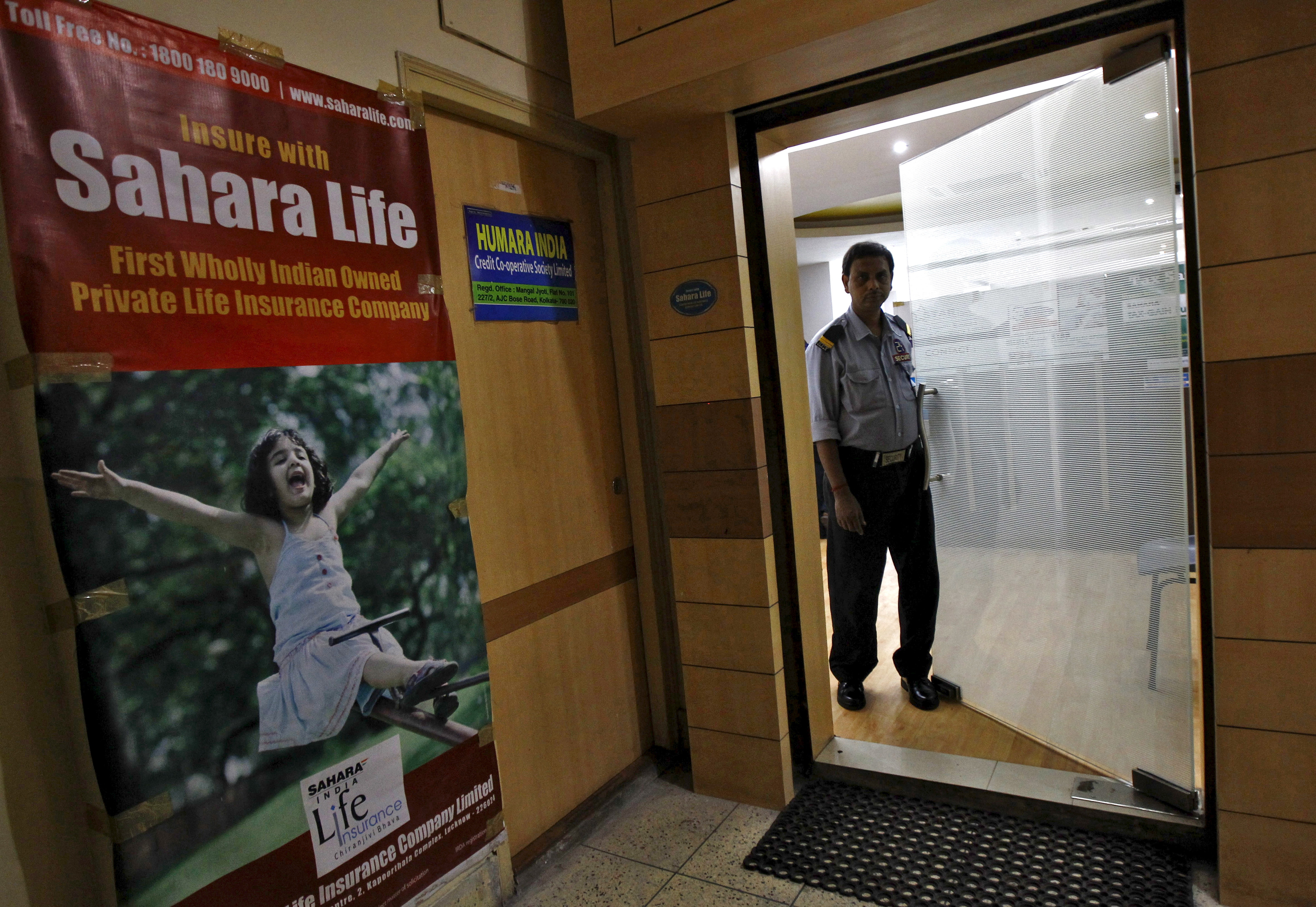 A private security guard stands on the door of a Sahara India Life Insurance office in Kolkata