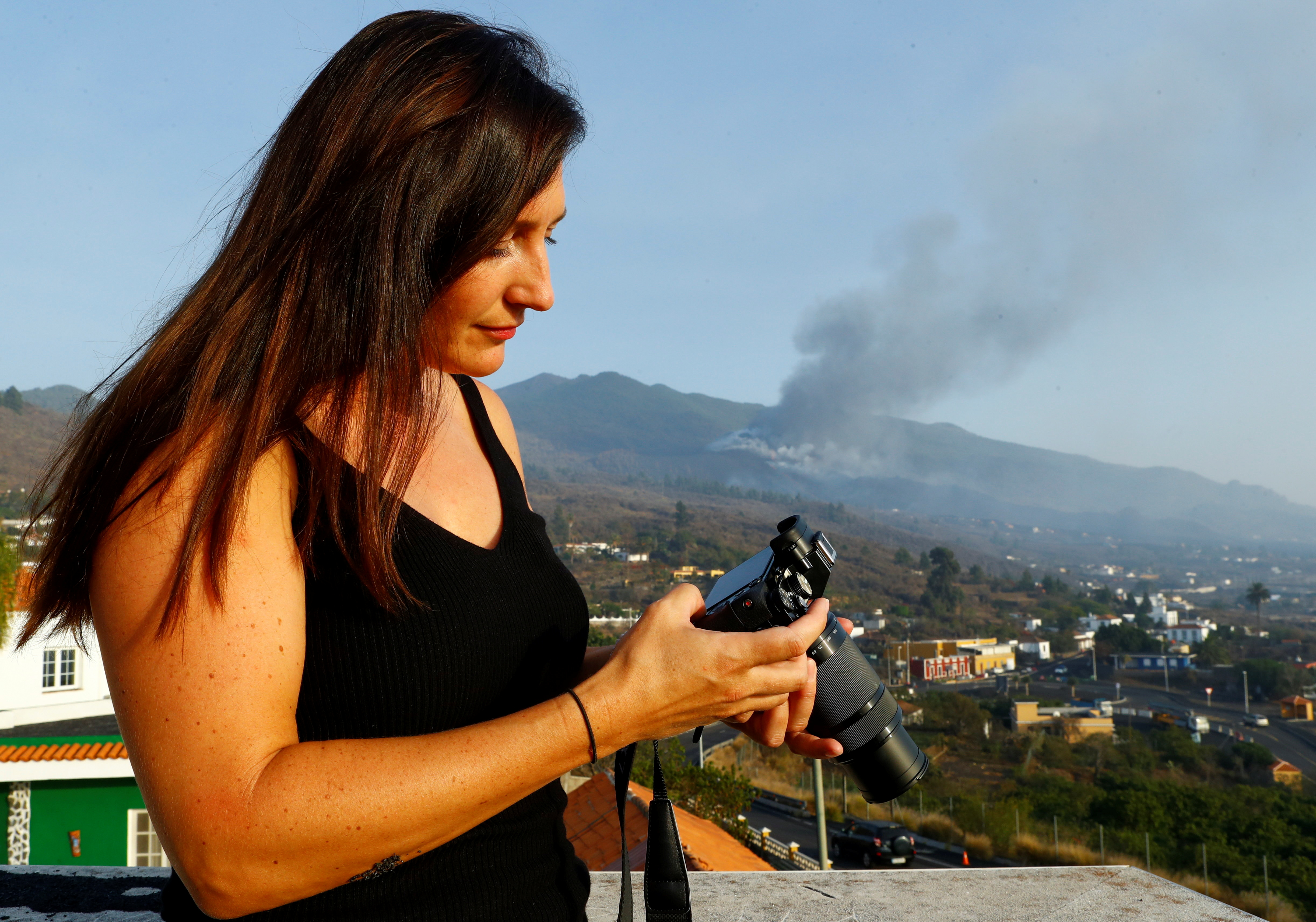 Czech Eva Kubelkova, a volcano hunter based in the Azores, checks her camera with the Cumbre Vieja volcano in the background, in El Paso