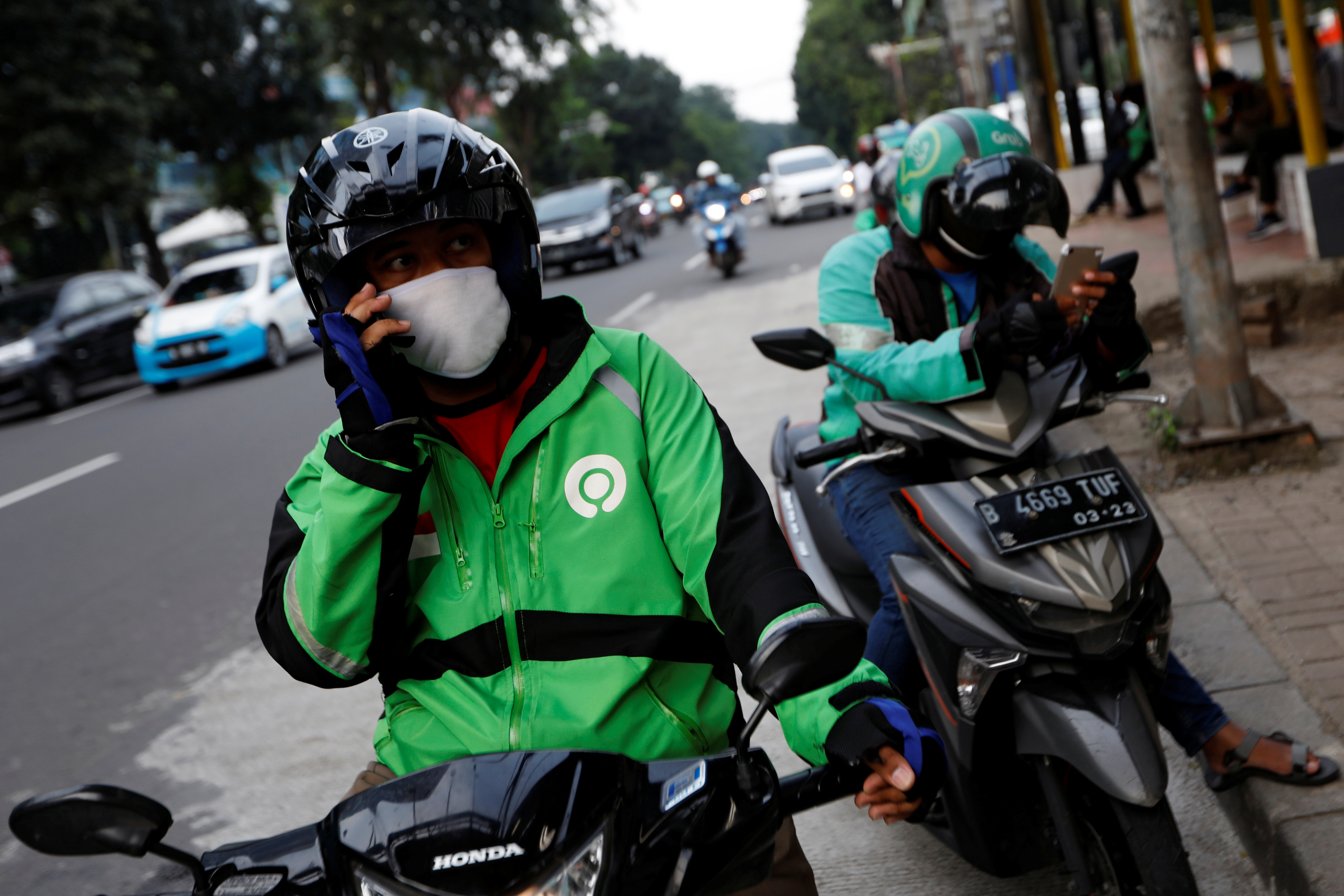 Online motorbike taxi drivers use their smartphones while waiting for customers in Jakarta