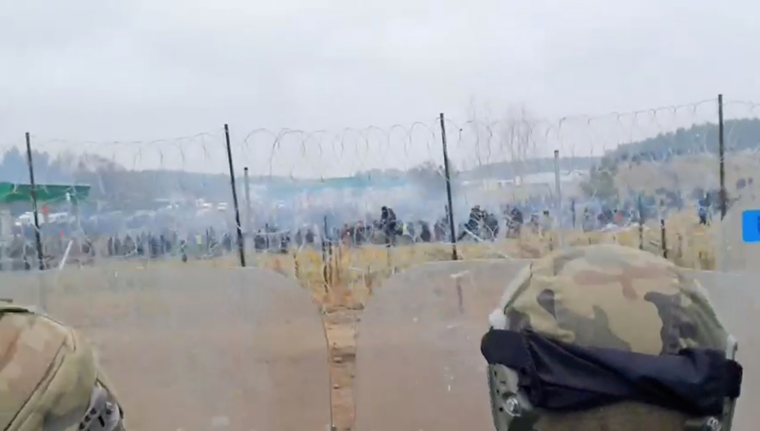 A still image, taken from a handout video released by the Polish Defence Ministry, shows Polish service members standing guard in front of a fence, as migrants attempt to cross the Belarusian-Polish border at Kuznica - Bruzgi checkpoint, Poland, November 16, 2021. MON/Handout via REUTERS  