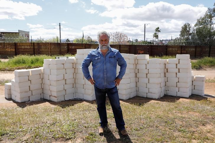 Canadian-born artist Cosimo Cavallaro poses for a portrait while building a wall made of cheese with his crowd funded project next to a portion of the U.S.-Mexico border wall near Tecate, California