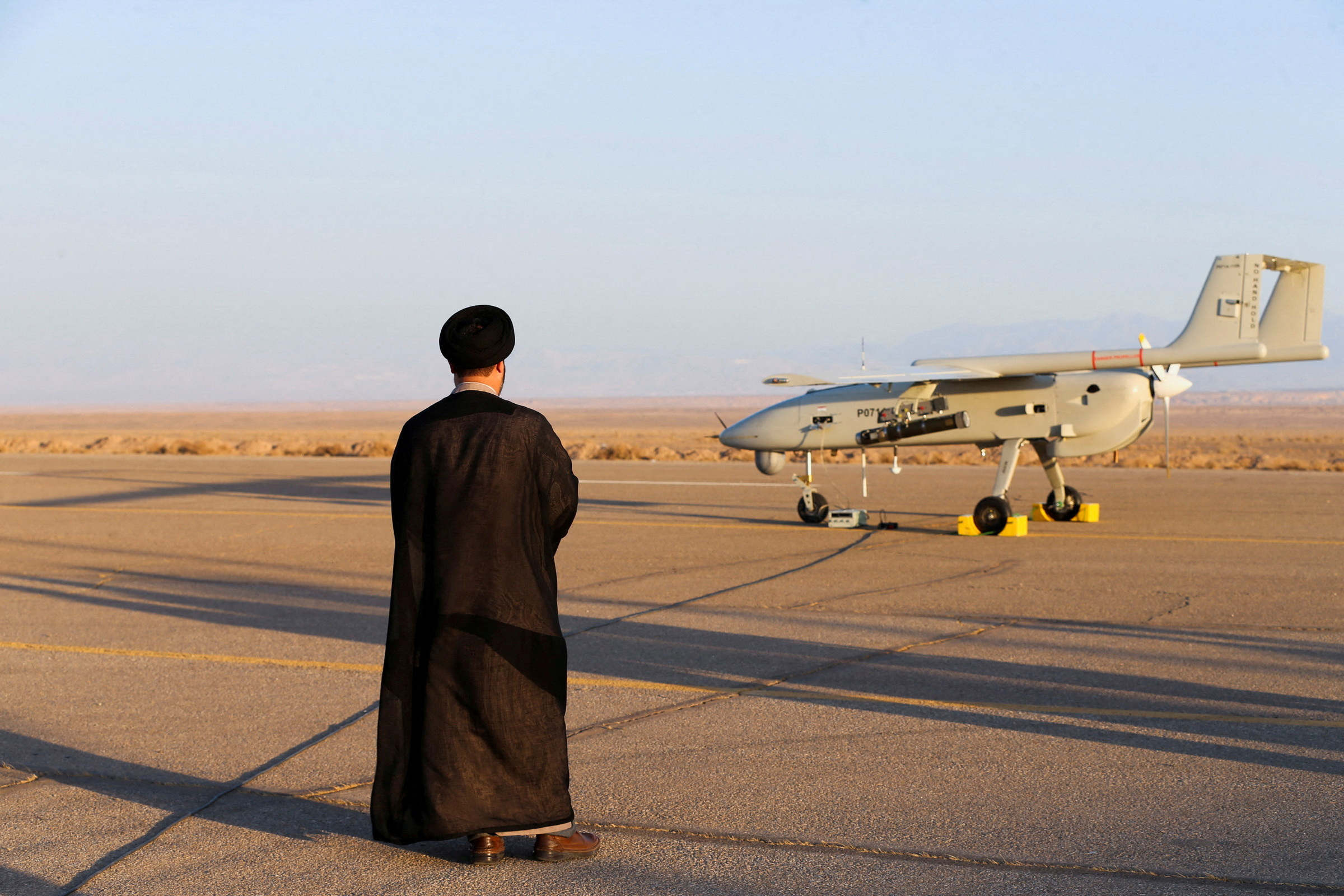An Iranian cleric stands near a drone during a military exercise in an undisclosed location in Iran