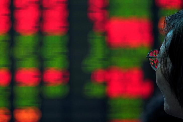 An investor looks at an electronic board showing stock information at a brokerage house in Shanghai