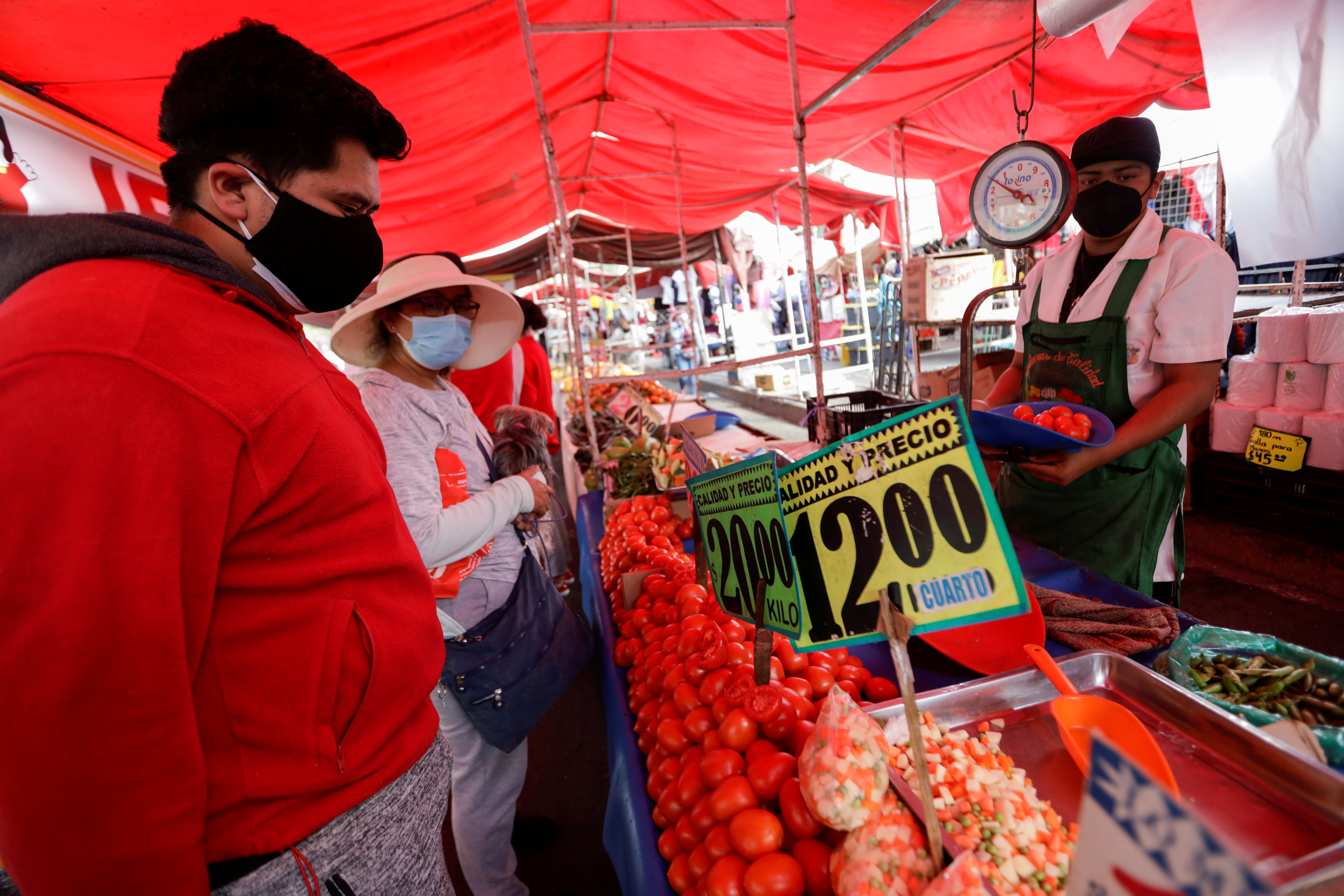 Customers buy tomatoes at a street market, in Mexico City