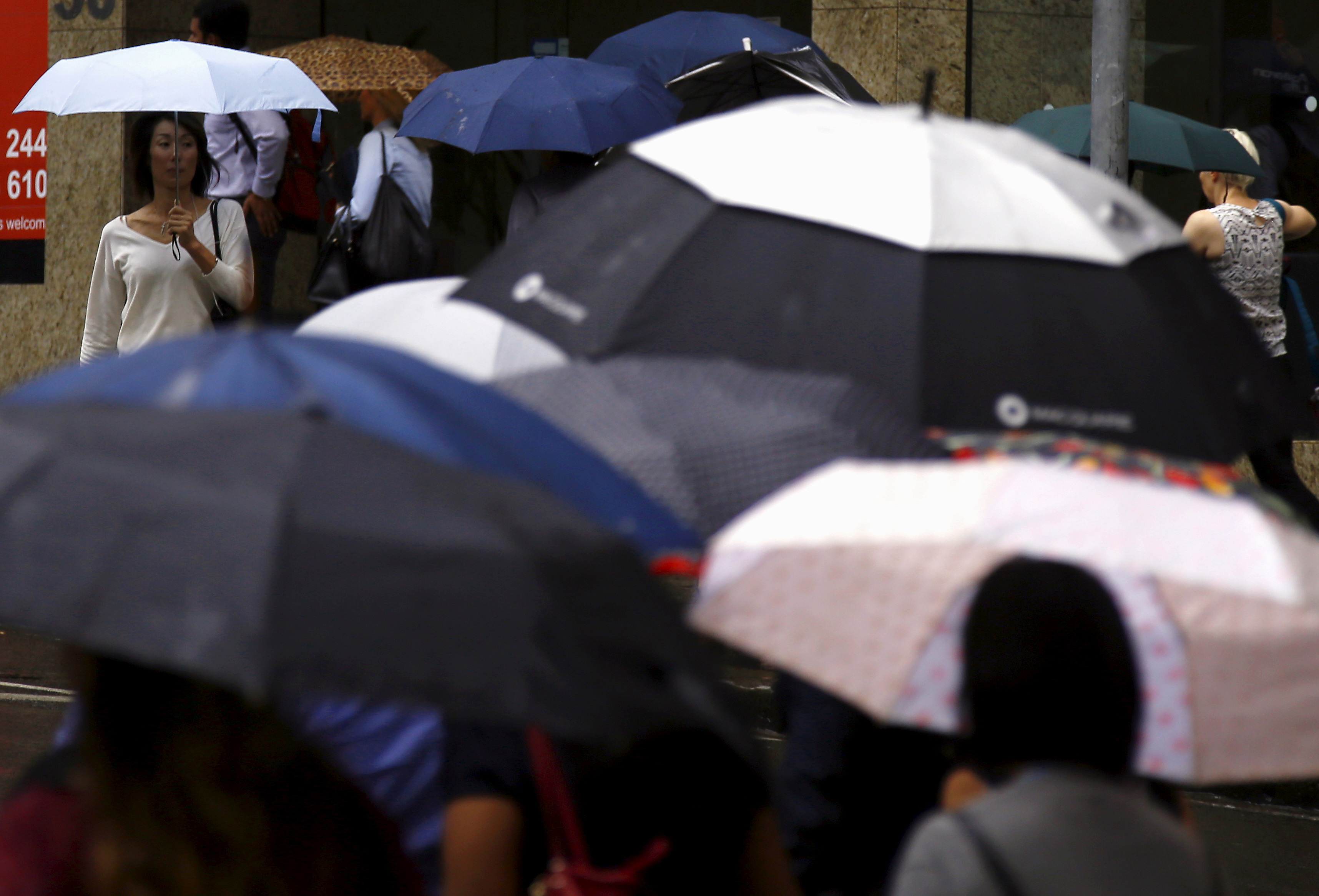 Pedestrians hold umbrellas as they walk to office buildings on a rainy morning in central Sydney, Australia