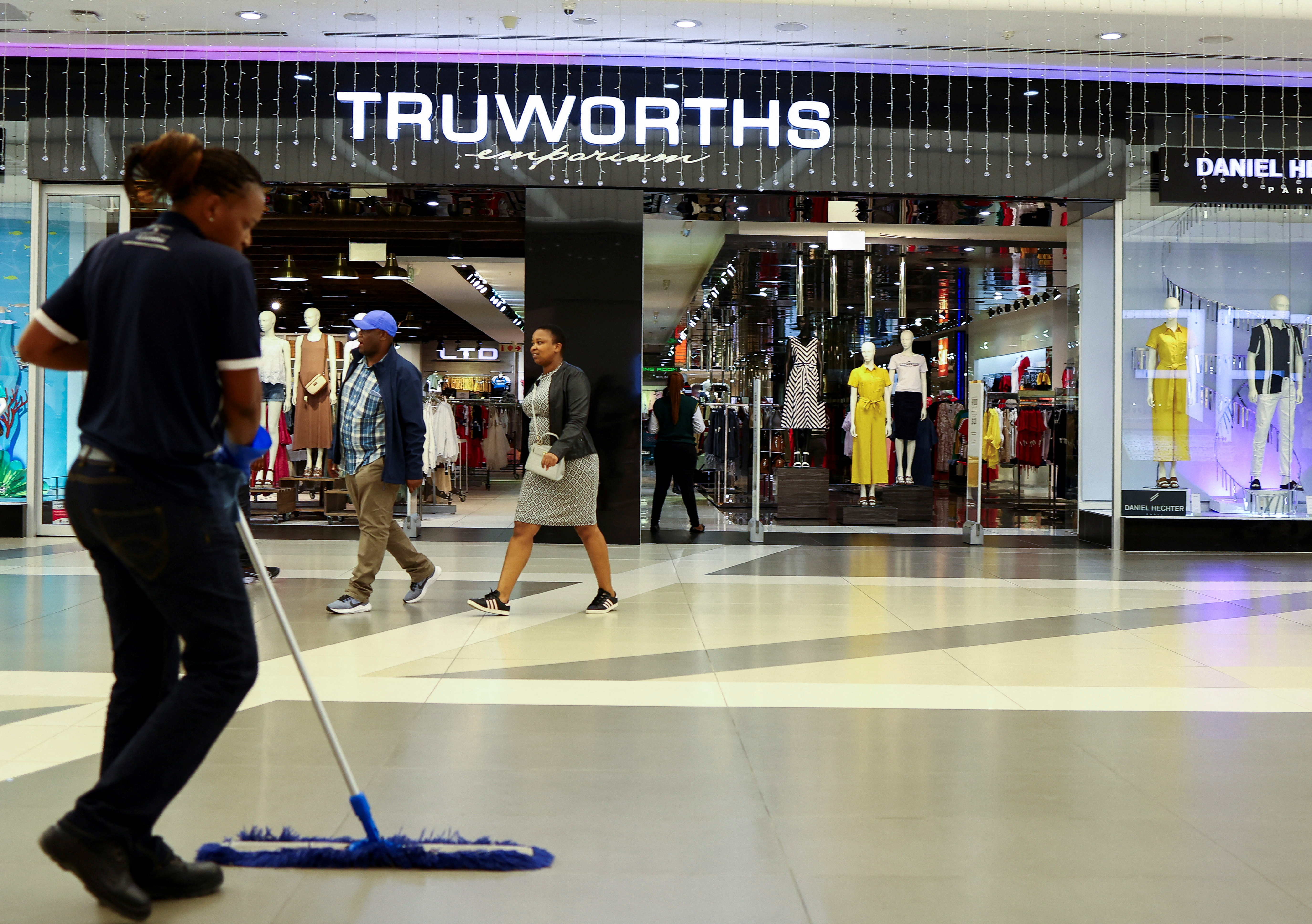 A worker cleans in front of a Truworths shop, in Johannesburg